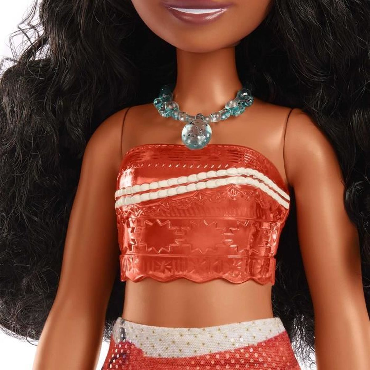 Una muñeca que lleva un top rojo con rayas blancas, un collar azul y pelo negro. La muñeca tiene un tono de piel bronceado.
