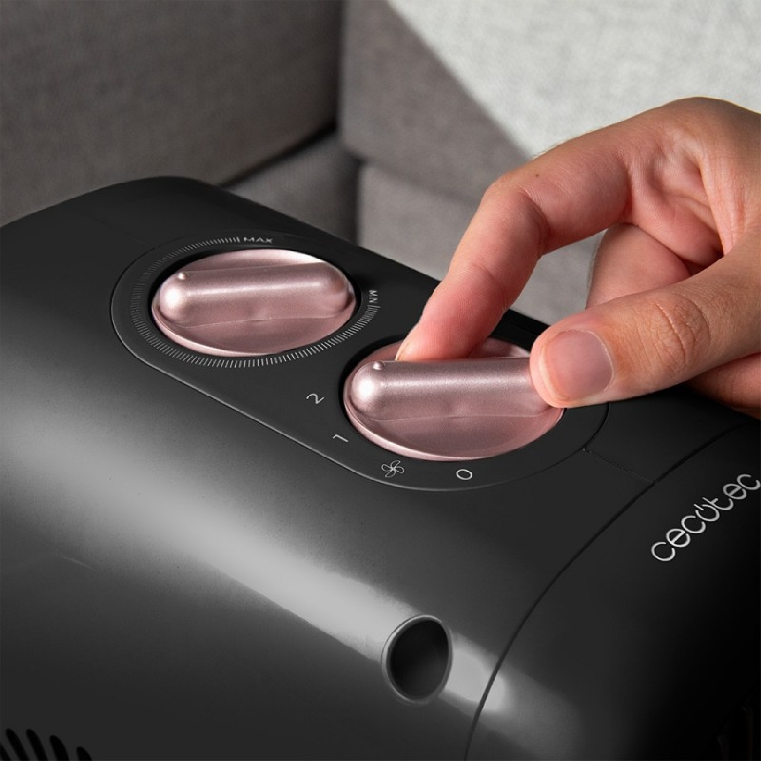 Una mano gira una manopola color oro rosa su un dispositivo nero. Il dispositivo ha due manopole e il marchio 'Cecotec' è visibile.