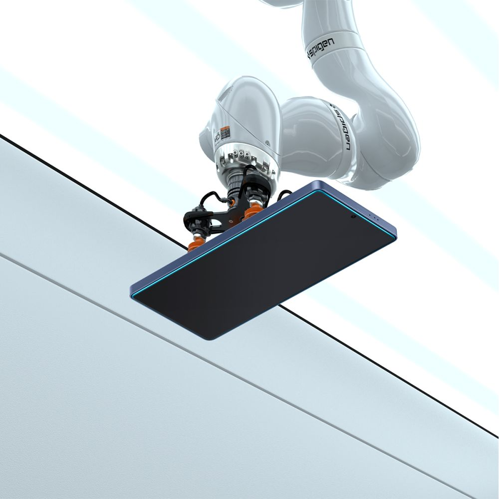 Ramię robota trzyma ciemny telefon z niebieską obwódką. Ramię jest białe, a tło to biała ściana z jasnoniebieskimi liniami.