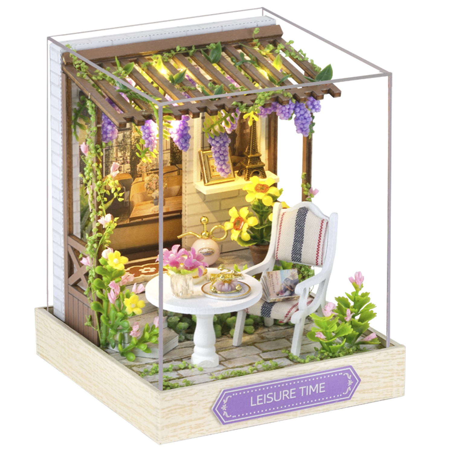 Scena di giardino in miniatura: pergolato con uva, tavolo con fiori, sedia e un piccolo modello della Torre Eiffel, il tutto all'interno di una scatola di vetro.