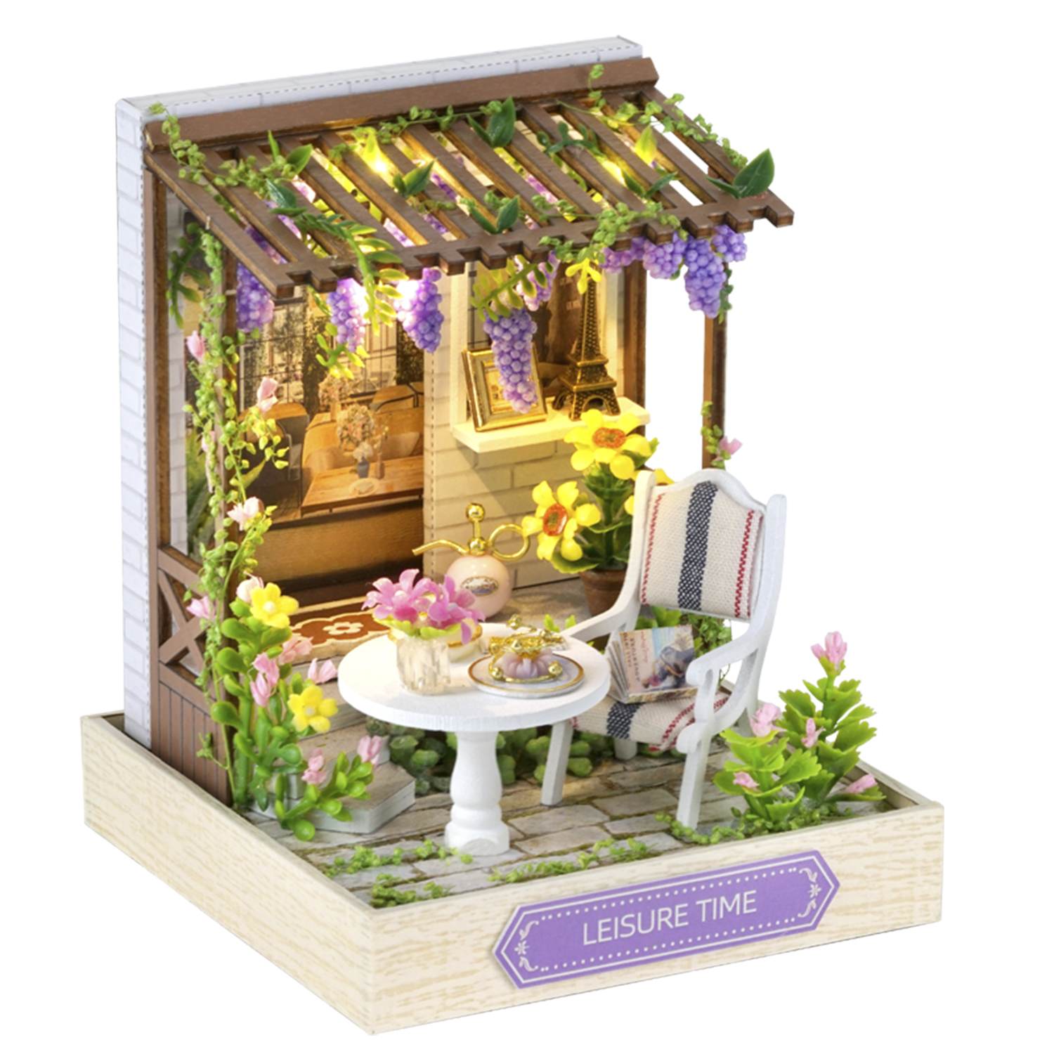 Scena di giardino in miniatura: pergolato con uva, tavolo, sedia, fiori e modello della Torre Eiffel. Cartello con scritto 'LEISURE TIME'.