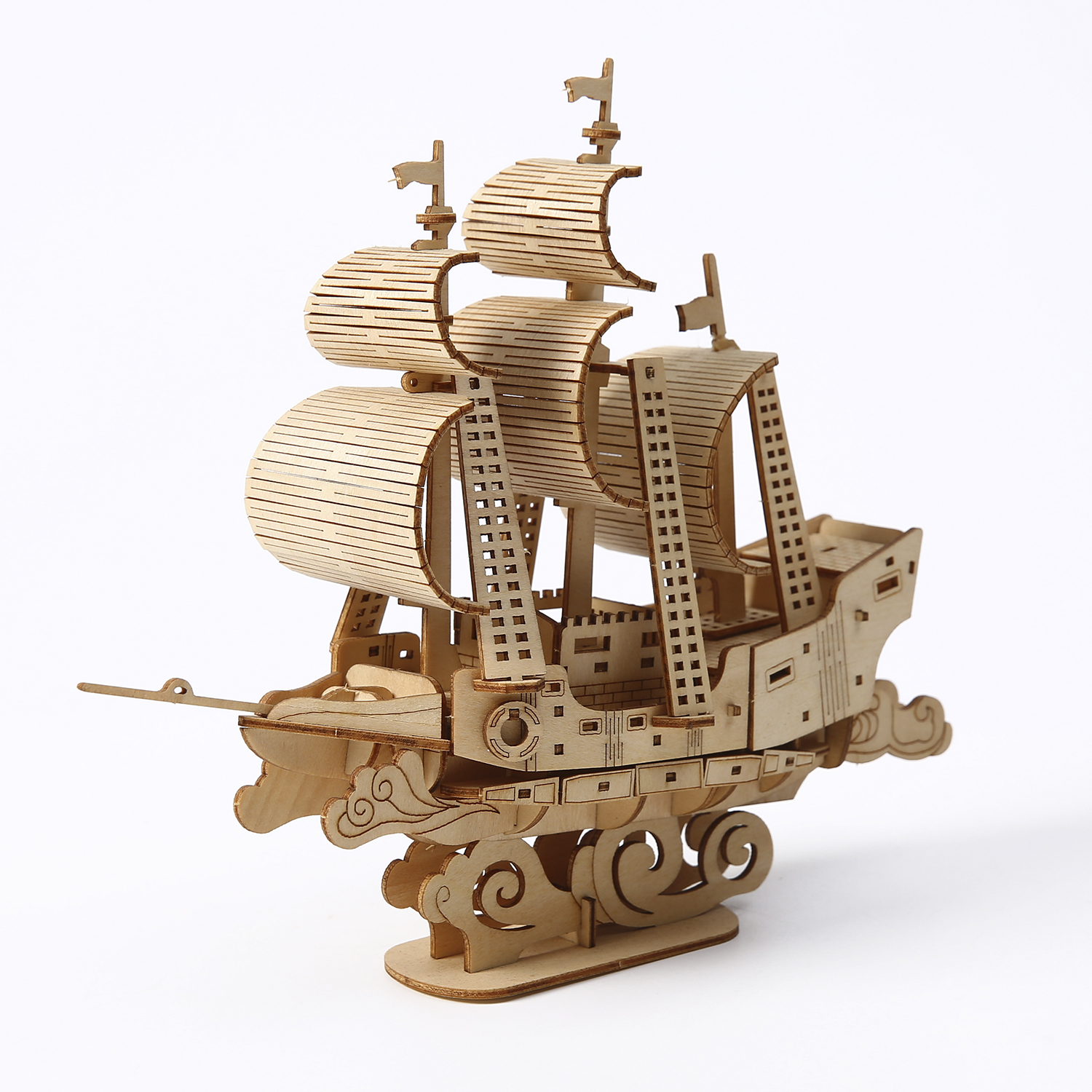 Un modello di nave in legno su una superficie bianca. Ha vele dettagliate, alberi e una base decorativa a forma di onde.