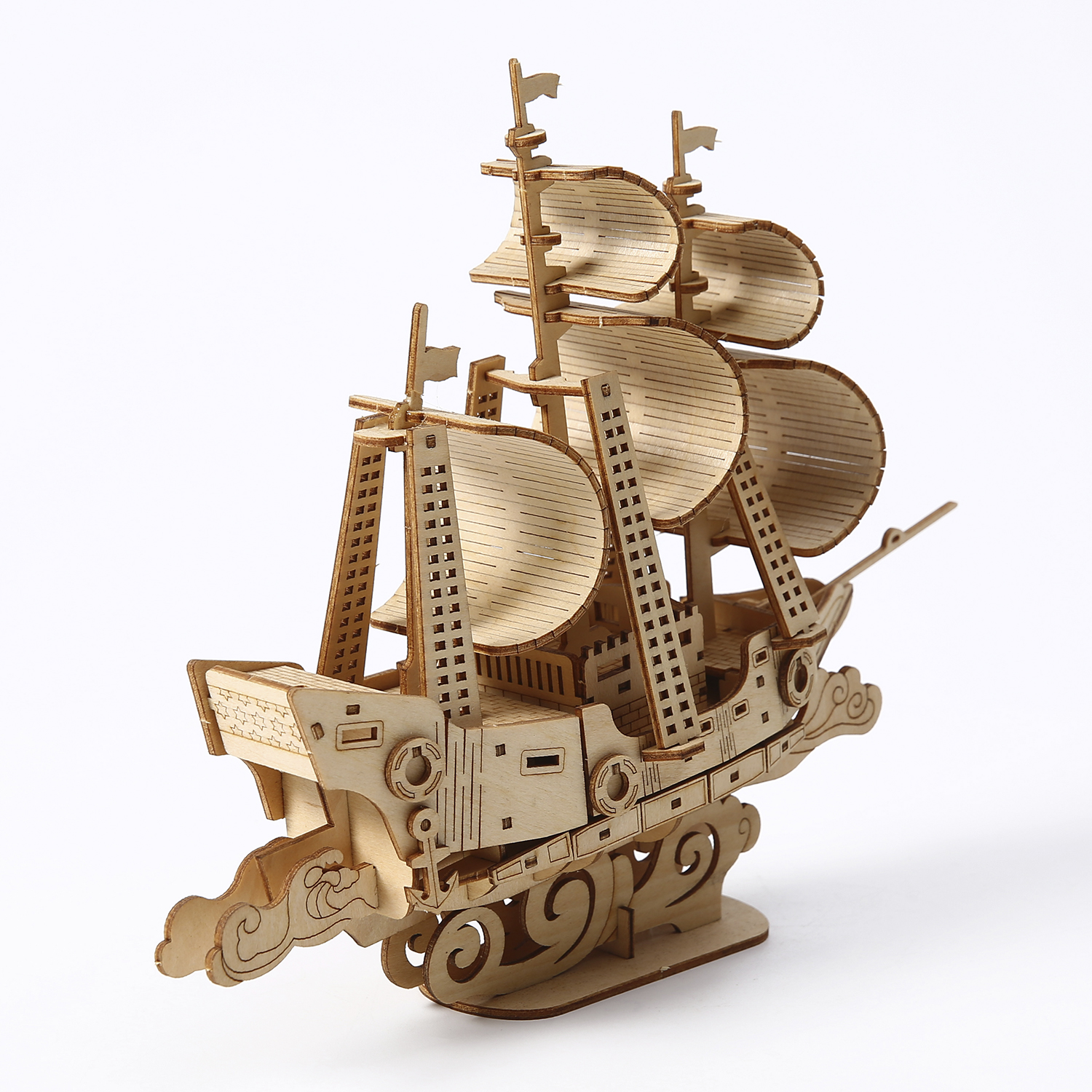 Modello di nave in legno su sfondo bianco. Presenta vele, bandiere e base decorativa. Colore marrone chiaro, costruzione dettagliata.