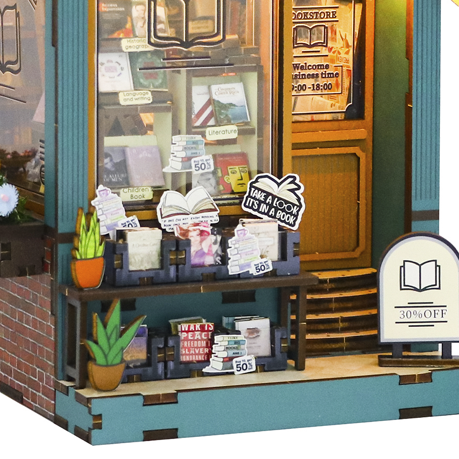 Un modello in miniatura di libreria con libri, scaffali, piante e un cartello con il 30% di sconto. Il negozio ha una porta in legno e un muro di mattoni.