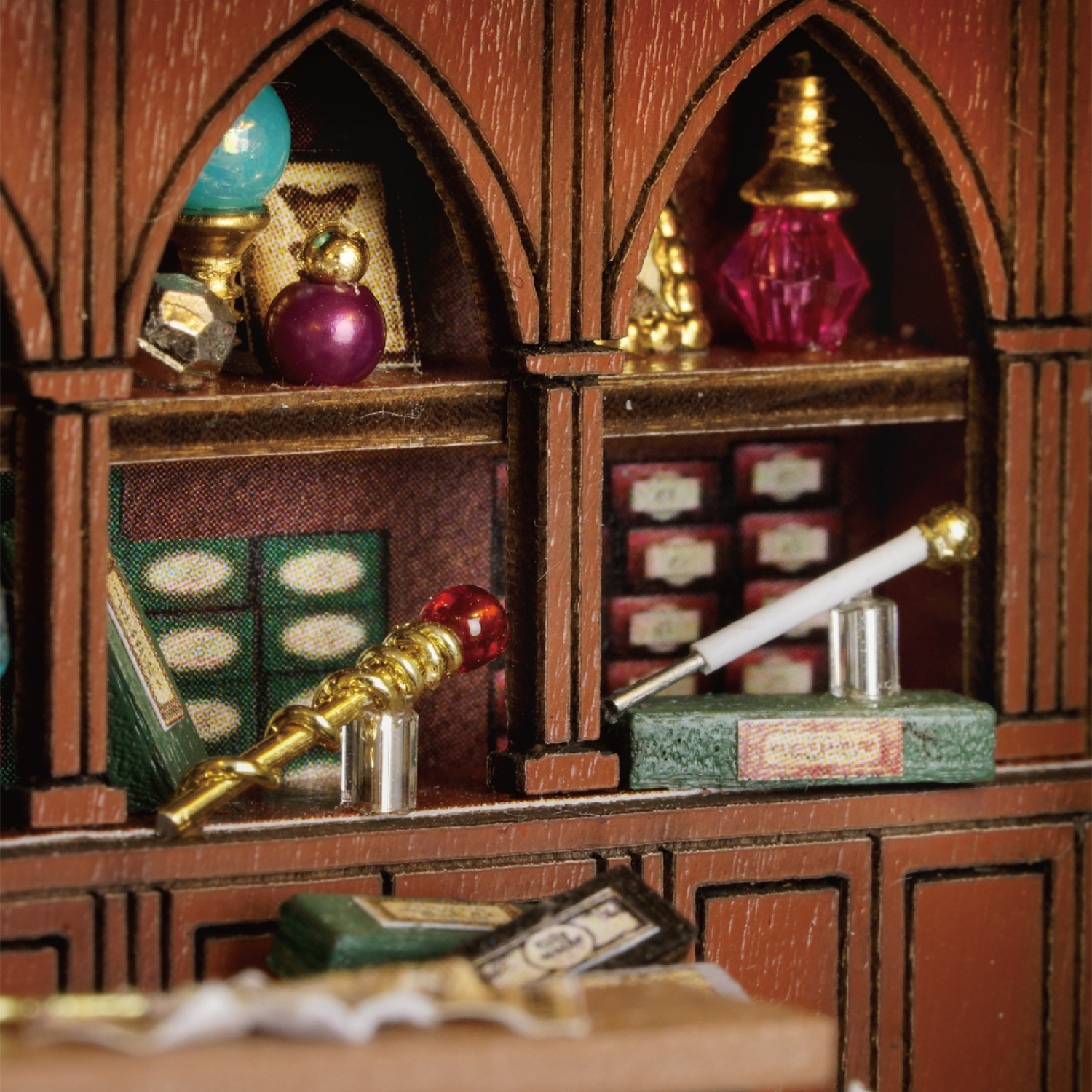 Miniatur-Holzschrank mit gewölbten Regalen, die Zaubertränke, Bücher und einen goldenen Stab mit einem roten Edelstein enthalten.