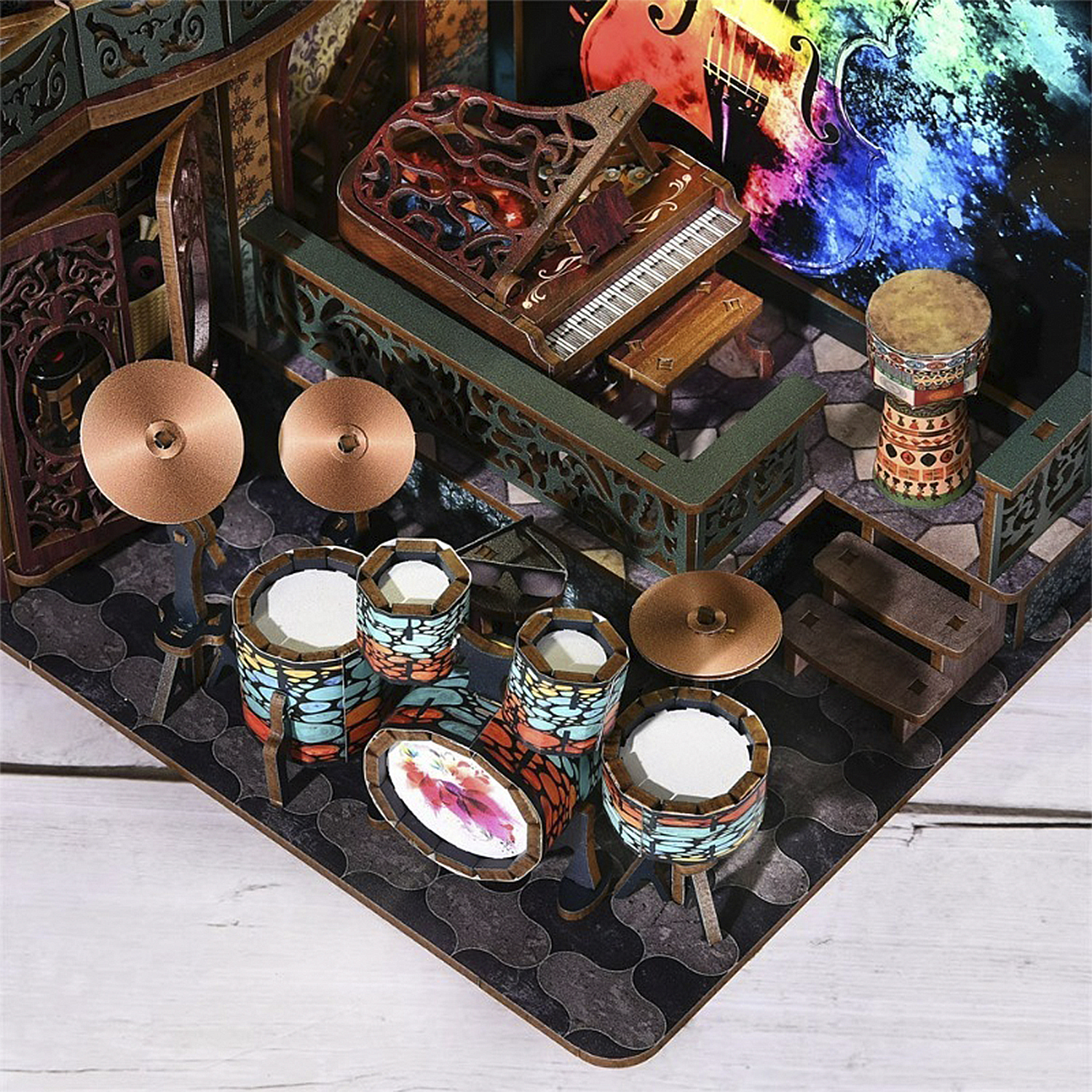 Miniatur-Musikzimmer: Trommeln, Klavier, Becken und eine farbenfrohe Kulisse einer Geige. Holzkonstruktion mit filigranen Details.