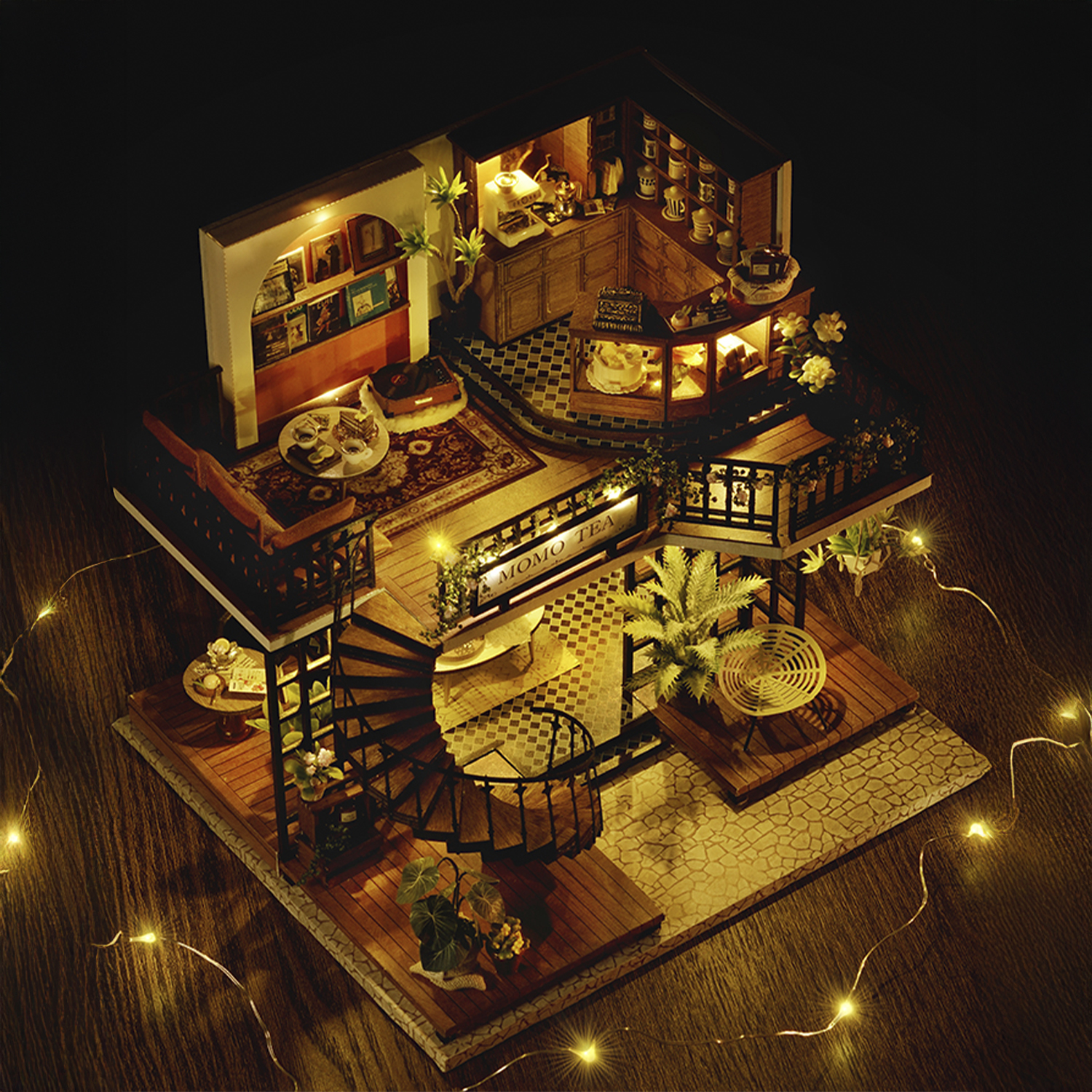 Modello di caffè in miniatura con scala a chiocciola, tavoli e piante. Illuminato da luci calde, che mostra un interno accogliente e dettagliato.
