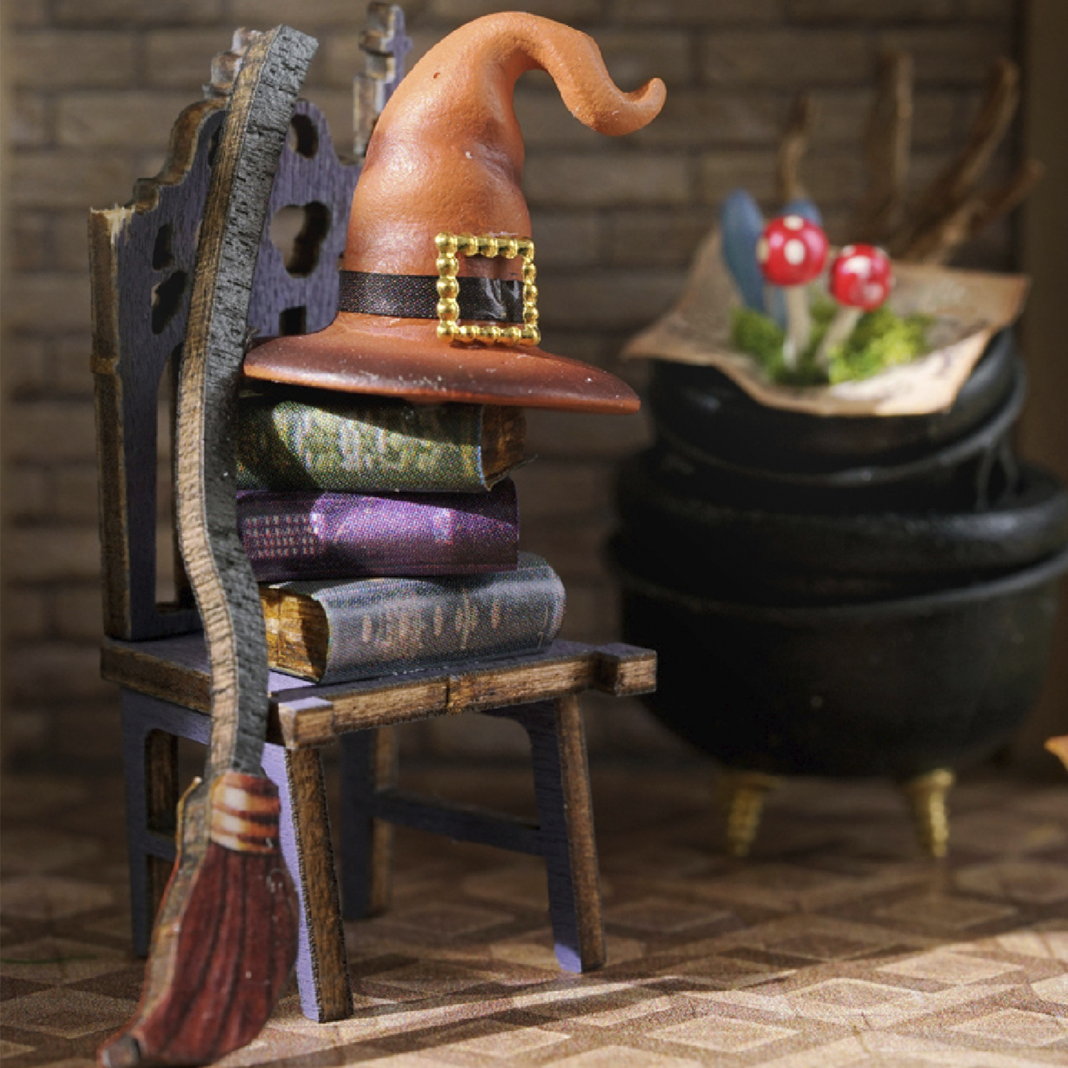 Scena di streghe in miniatura. Un cappello poggia su libri accanto a una scopa e un calderone con funghi. Scuro, spettrale.