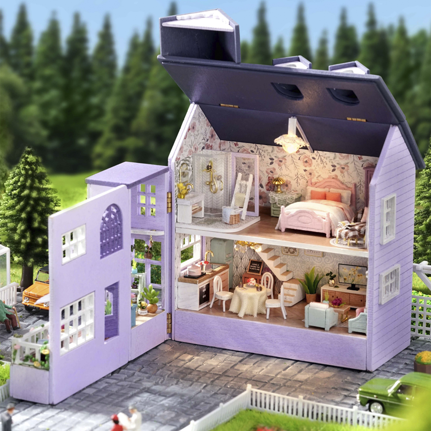 Una casa delle bambole dettagliata con pareti aperte, che mostra una camera da letto, una cucina e un bagno. Fuori, ci sono alberi e un'auto verde.