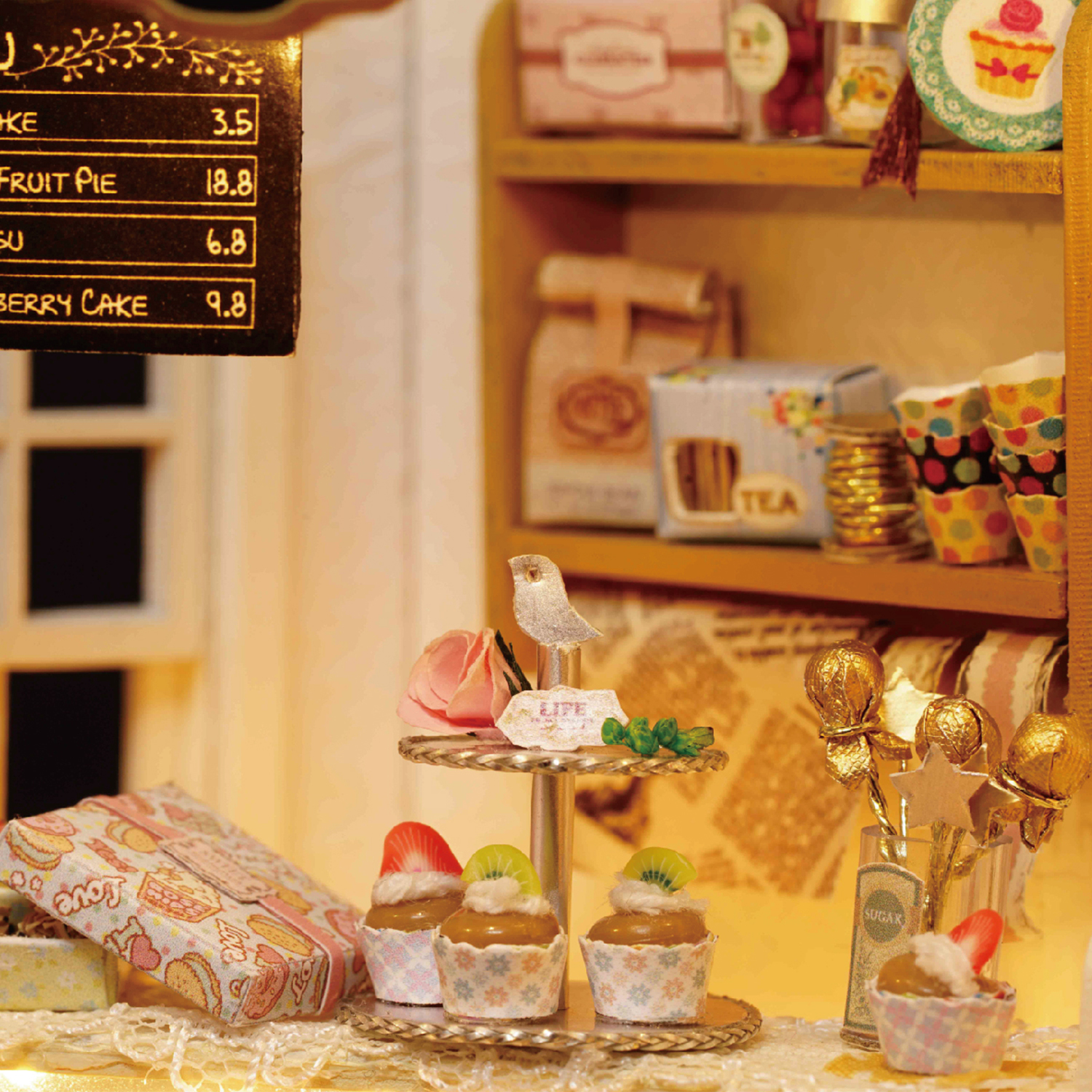 Miniatur-Bäckereiszene mit Cupcakes, Süßigkeiten und einer Speisekarte. Hintergrund mit Regalen, Teeboxen und Dekorationen.
