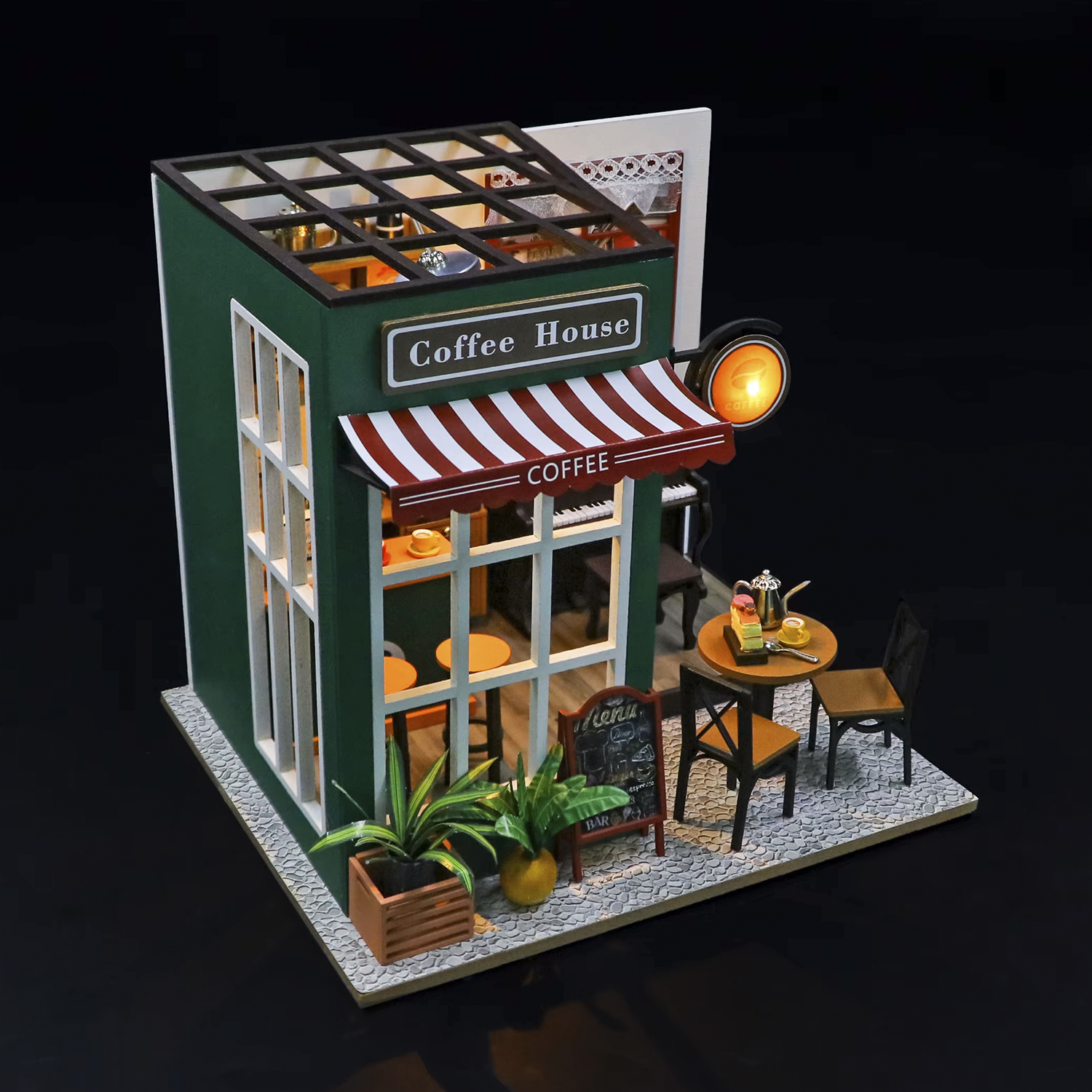 Mini bar con pareti verdi, tenda a strisce rosse e bianche, tavolini e piante. Un cartello dice 'Coffee House'.