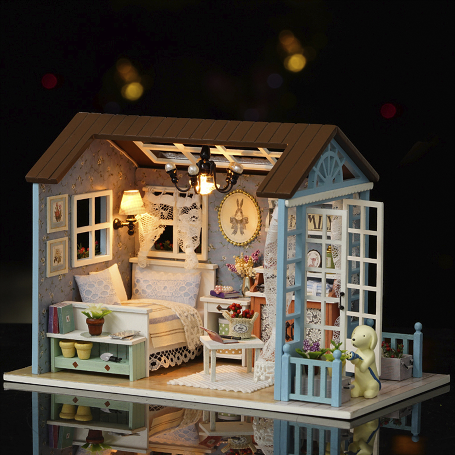 Miniaturhaus mit detaillierter Innenausstattung: Schlafzimmer, Balkon und Garten. Eine Hundestatue hält einen Schlauch. Das Haus ist braun und blau.