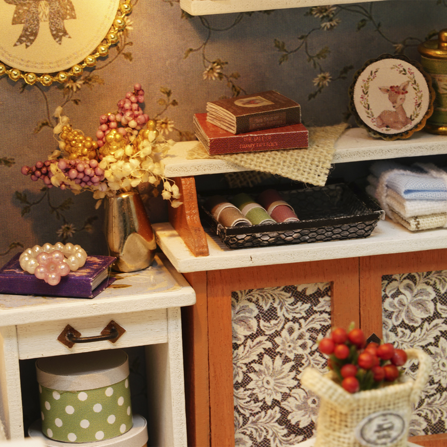 Miniatur-Raum-Szene mit Blumen, Büchern und dekorativen Gegenständen. Ein kleiner Tisch trägt Schmuck und eine Schachtel. Regale zeigen weitere Deko-Artikel.