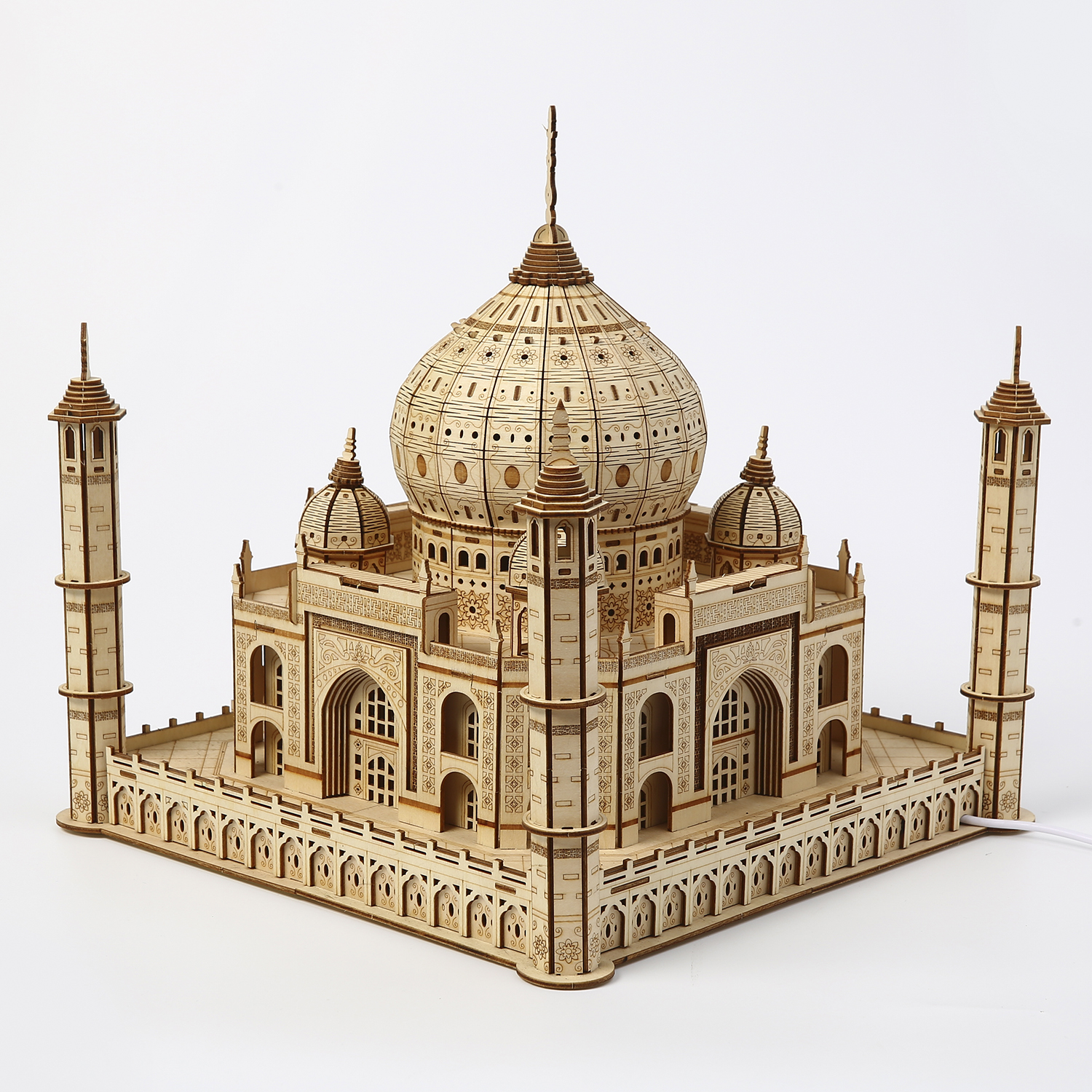 Un modello in legno del Taj Mahal su una superficie bianca. Presenta la cupola principale, cupole più piccole, minareti e intagli dettagliati.