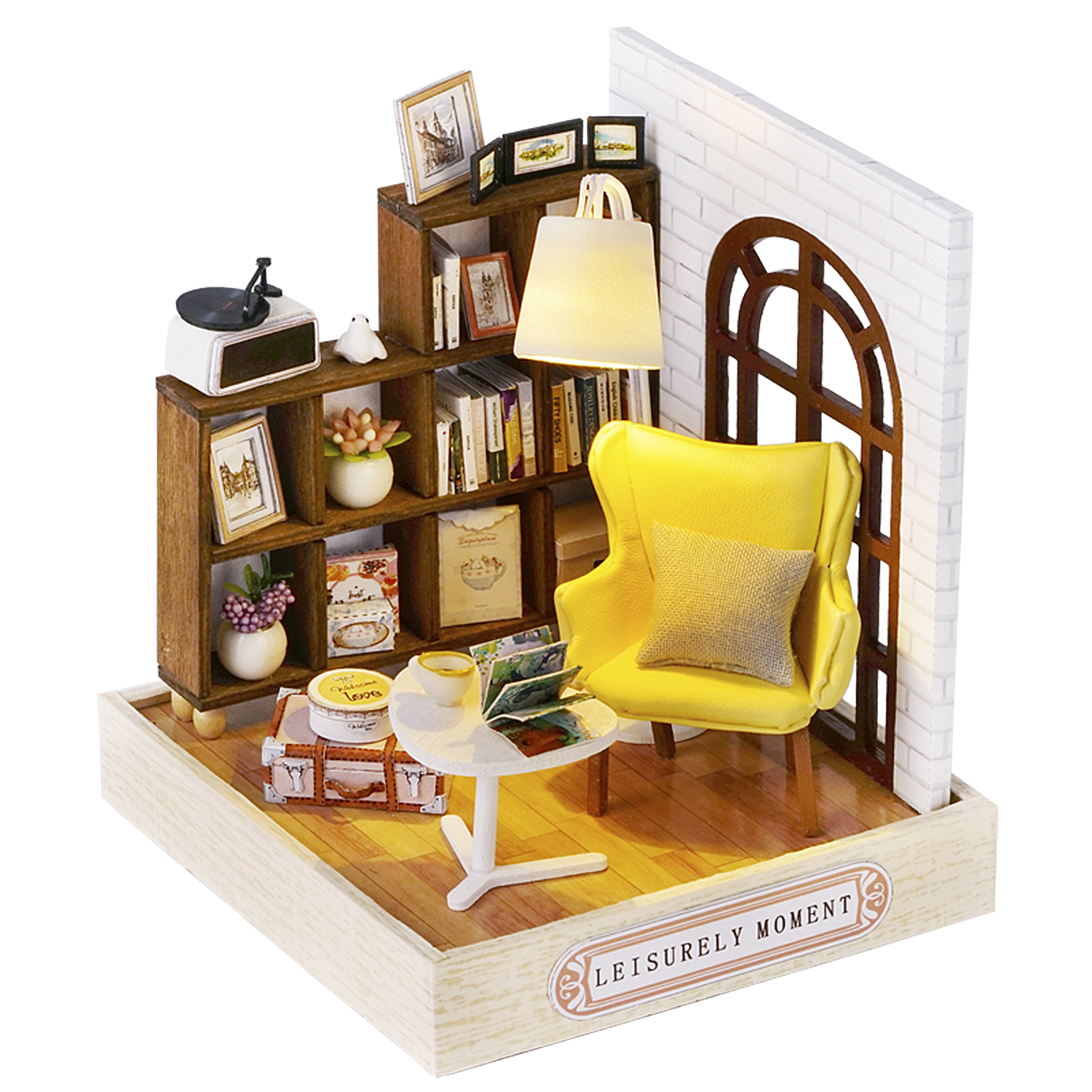 Scena di una stanza in miniatura con sedia gialla, libreria e finestra. Include un giradischi, libri e un tavolino.