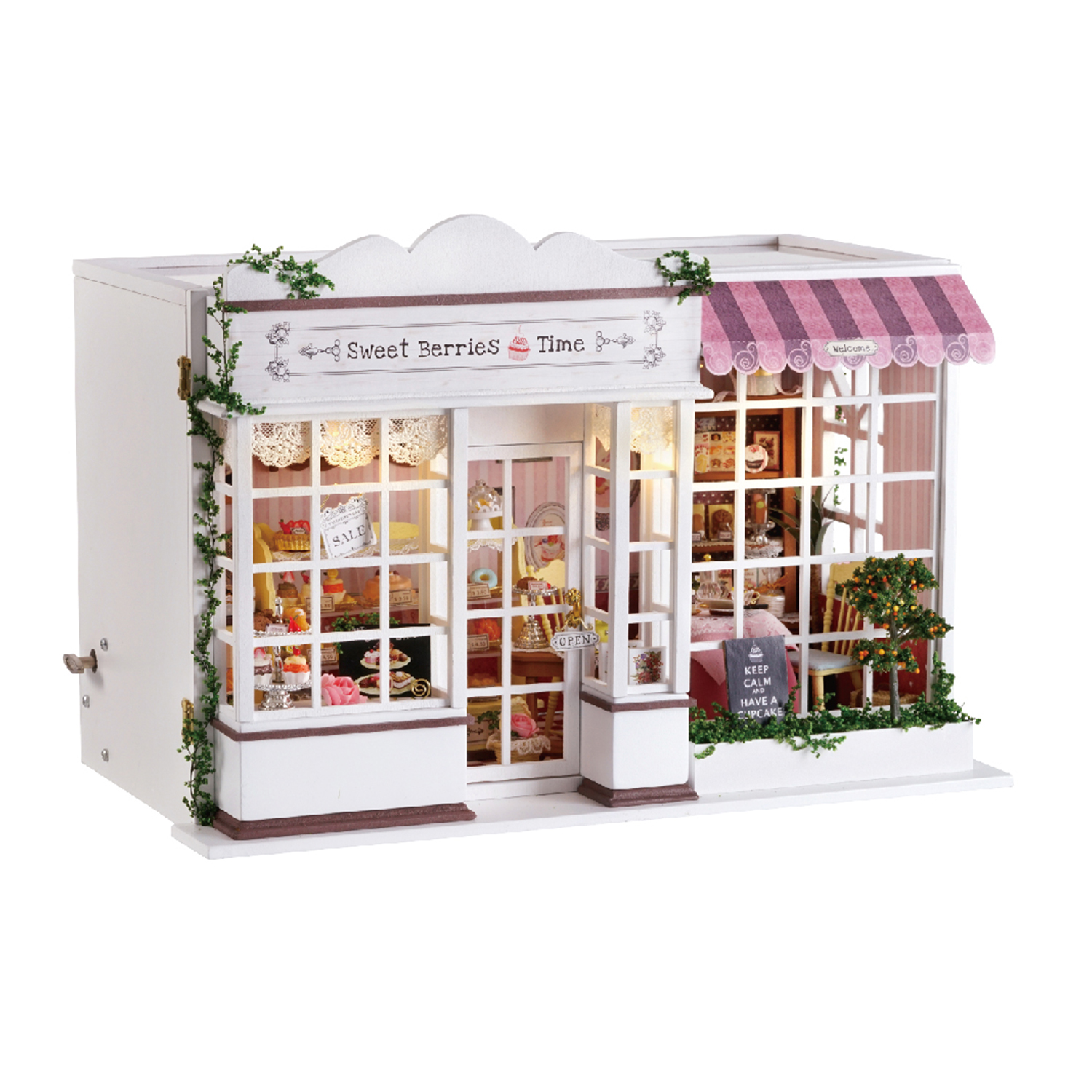 Una panetteria in miniatura con esterno bianco, tenda da sole rosa e interni dettagliati pieni di pasticcini e mobili in miniatura.