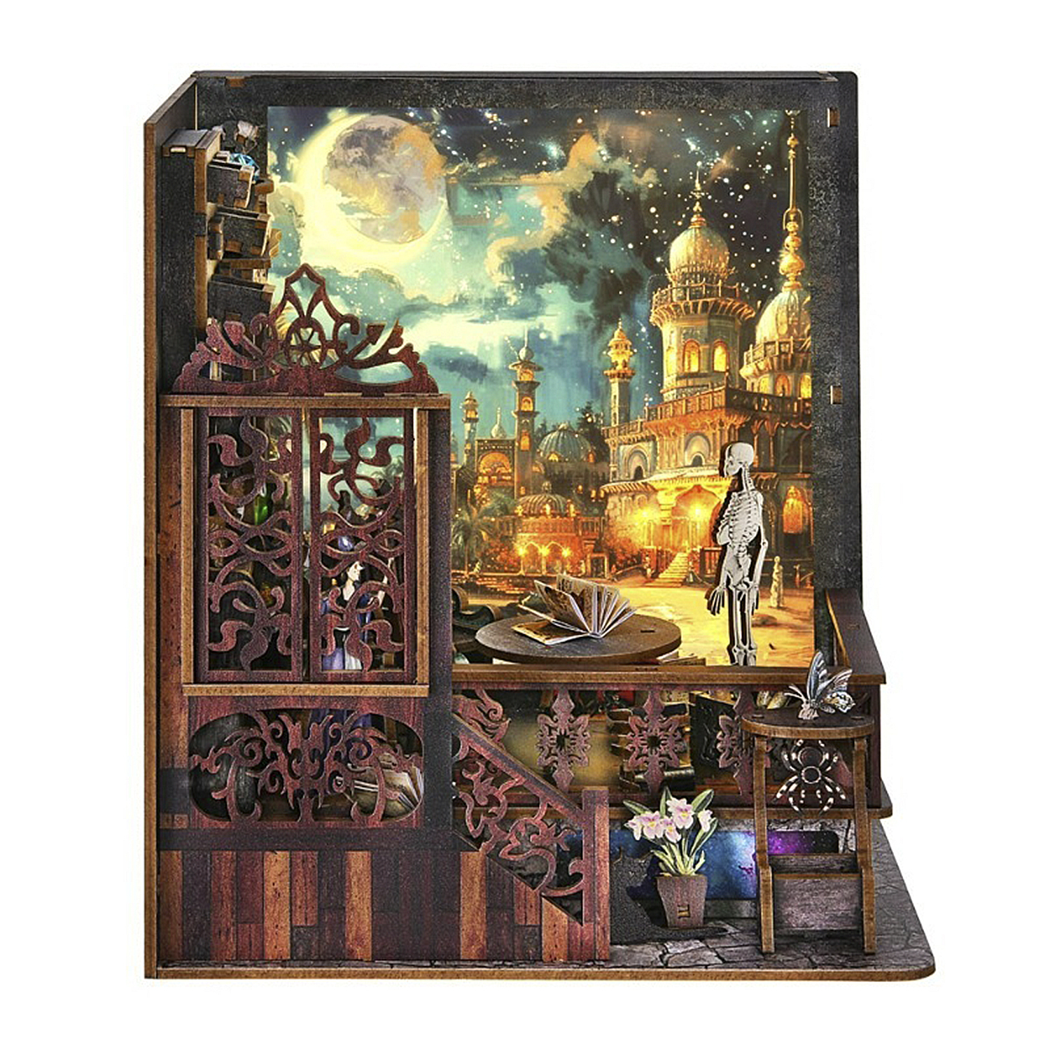 Un diorama in legno raffigura una scena cittadina illuminata dalla luna con uno scheletro, un libro aperto ed elementi decorativi. Include una farfalla e fiori.