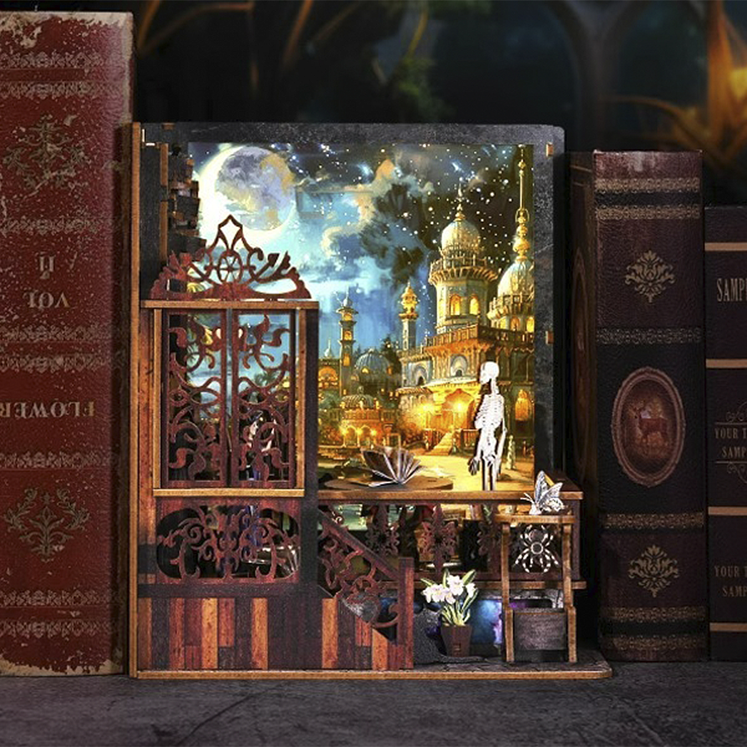 Un diorama di una città di notte con una figura di scheletro. La scena è all'interno di una cornice di legno, accanto a vecchi libri.