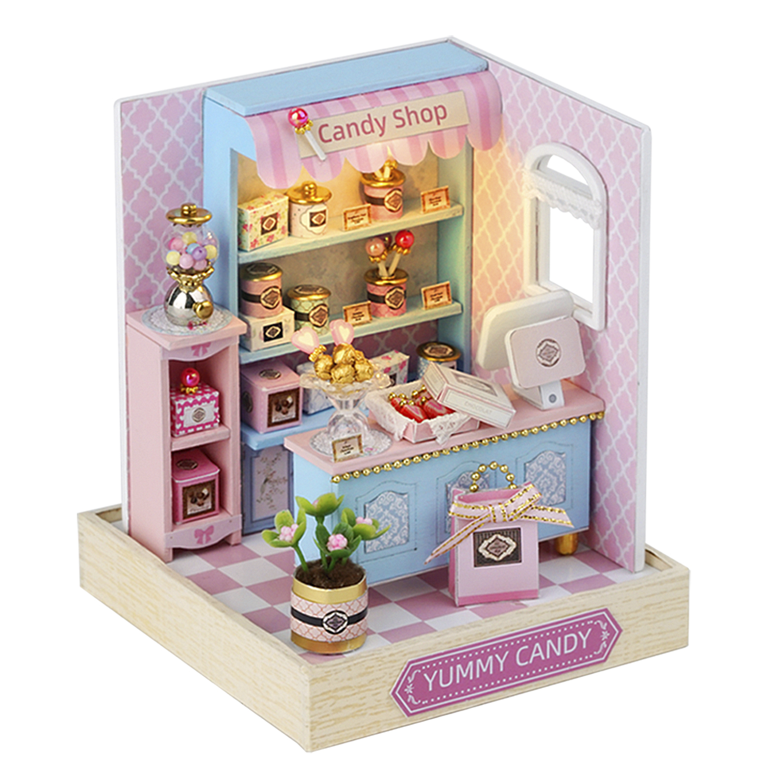 Miniatur-Süßwarenladen mit rosa Wänden, blauem Tresen, Regalen mit Süßigkeiten, Kaugummiautomaten und einer kleinen Pflanze.