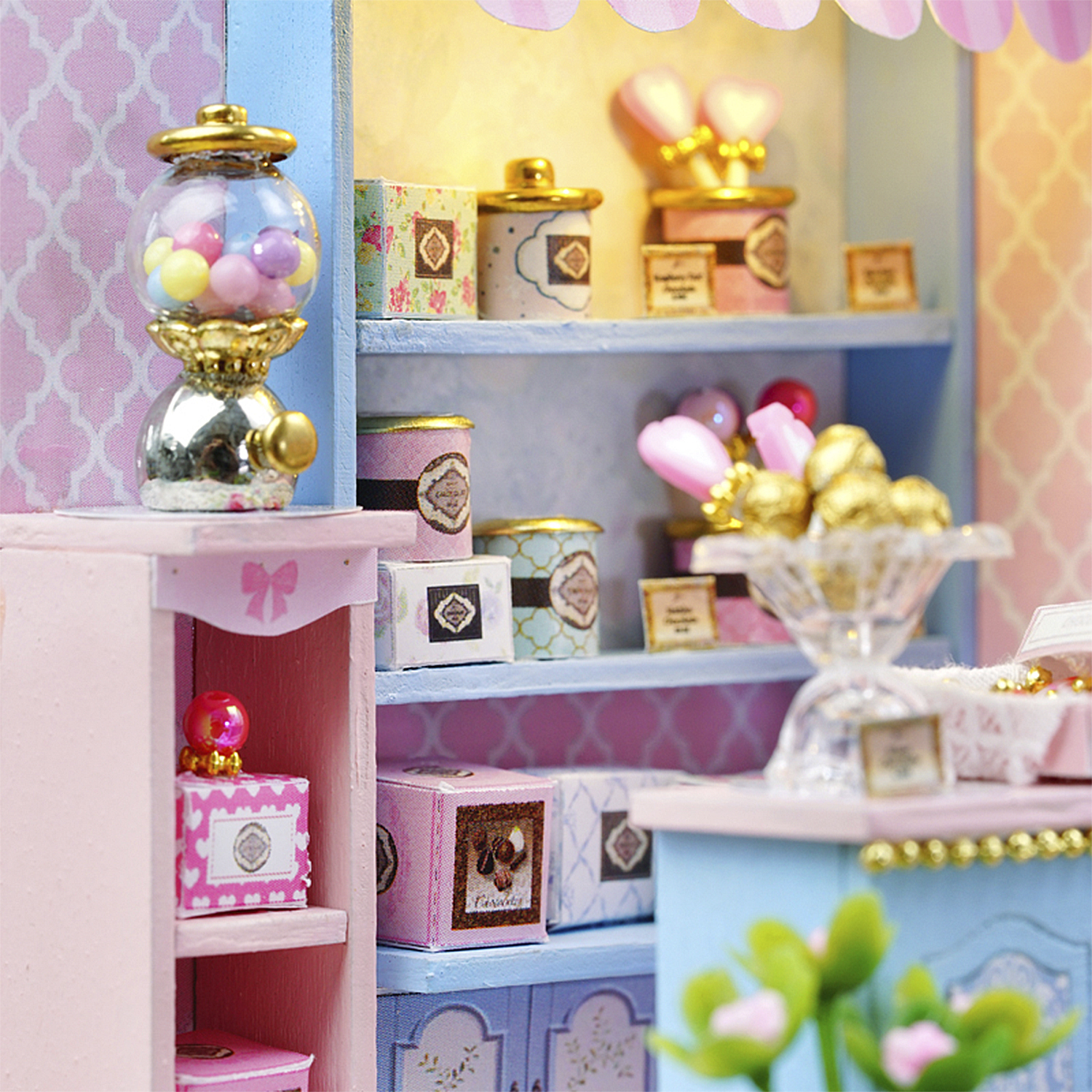 Miniatur-Süßwarenladen mit Kaugummiautomaten, Regalen mit Süßigkeitenboxen und Leckereien, in Rosa- und Blautönen.
