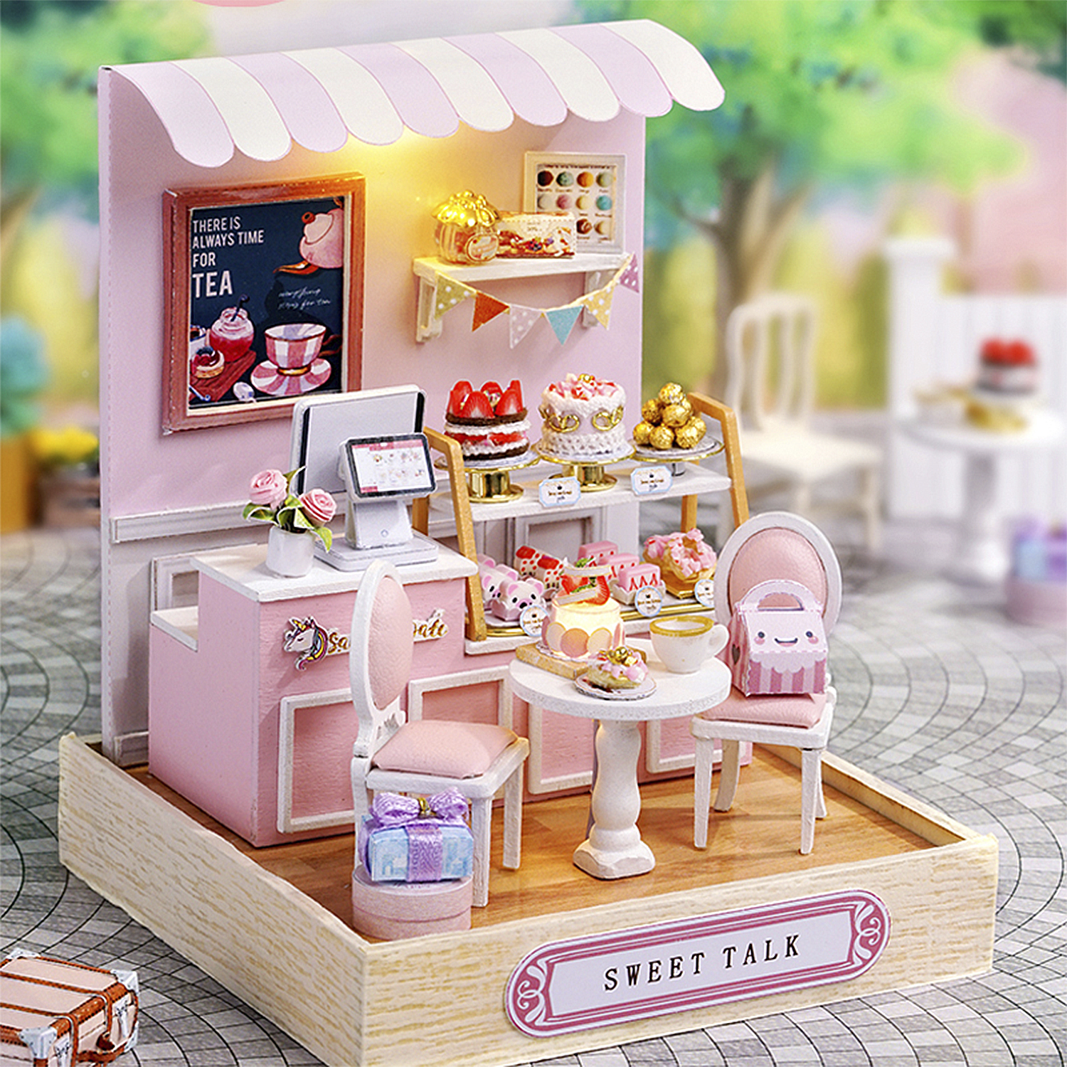Mini caffè rosa con torte, tavolo e sedie. Cartello: "C'è sempre tempo per il tè". Base in legno.