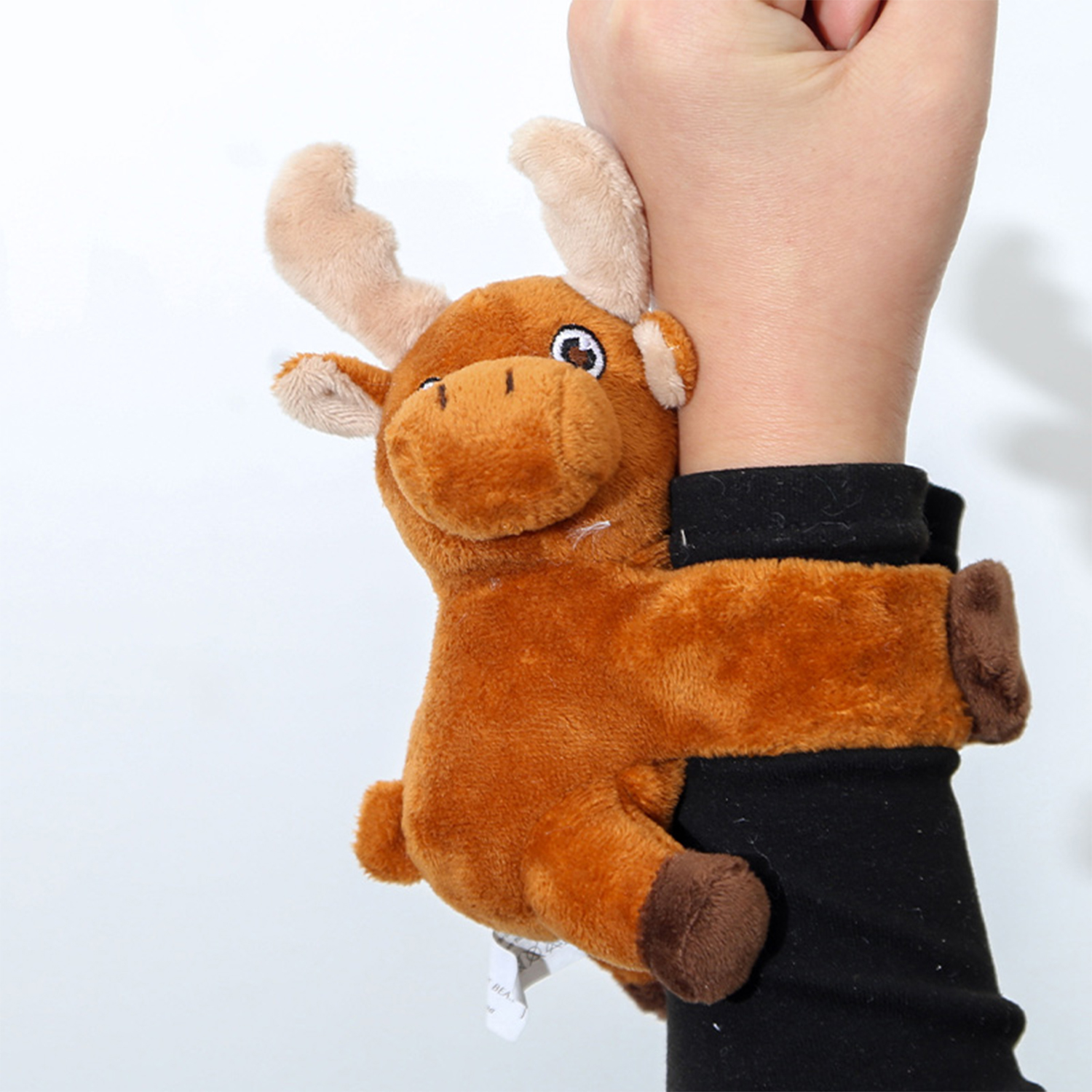 Un braccialetto di alce di peluche marrone è avvolto attorno al polso di una persona. Il braccialetto è marrone e nero, su sfondo bianco.