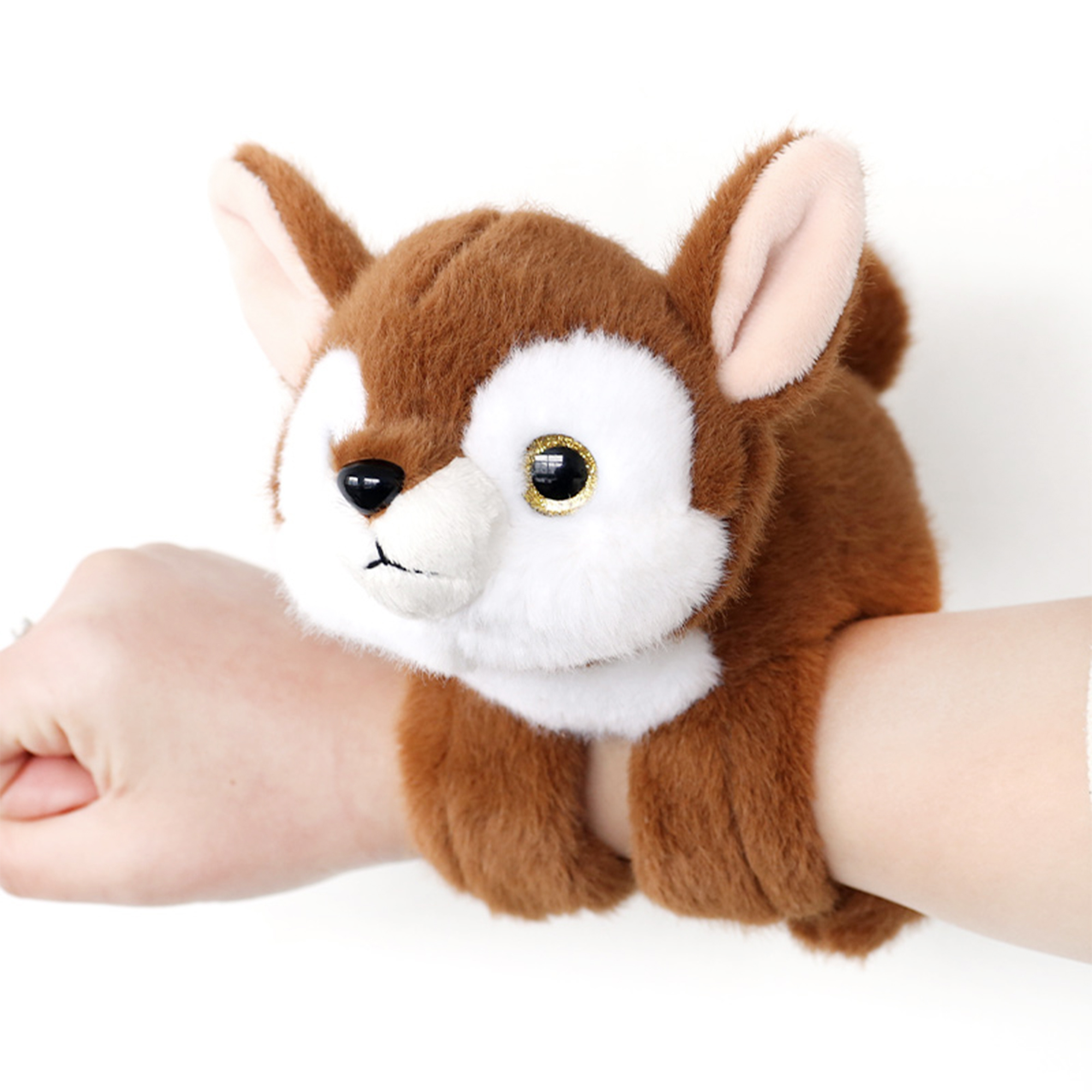 Un braccialetto di volpe di peluche marrone e bianco è indossato sul polso di una persona. Lo sfondo è bianco.