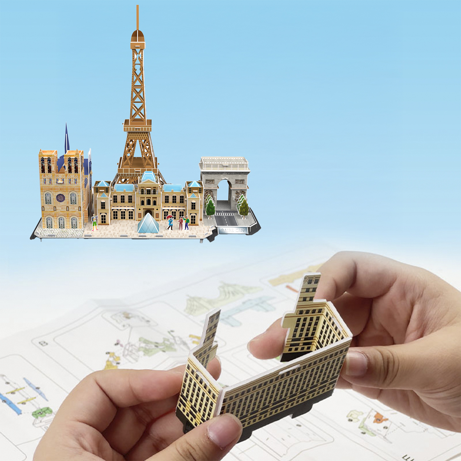 Una persona che assembla un puzzle 3D di monumenti parigini, tra cui la Torre Eiffel, l'Arco di Trionfo e Notre Dame, su sfondo blu.