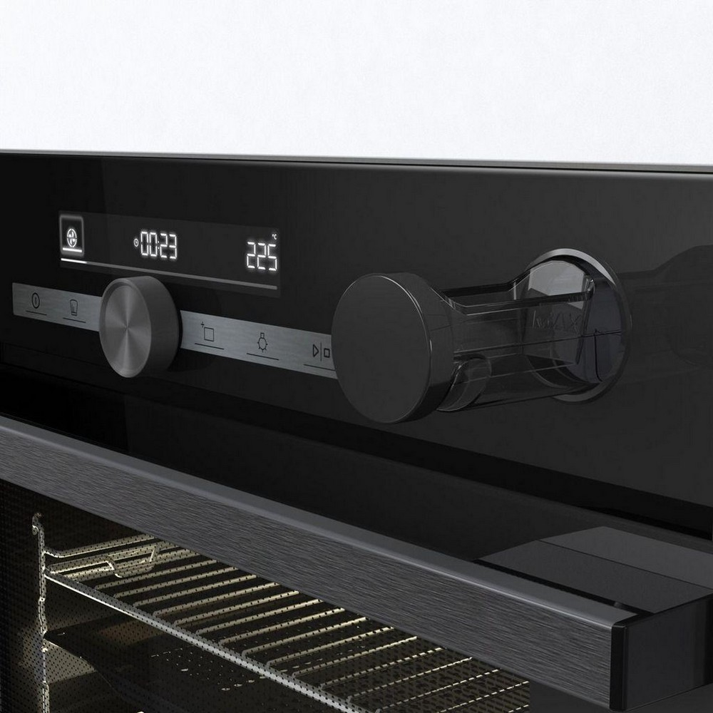 Un primo piano del pannello di controllo di un forno nero. Mostra manopole, un display digitale con numeri e una griglia del forno. Il forno è pulito.