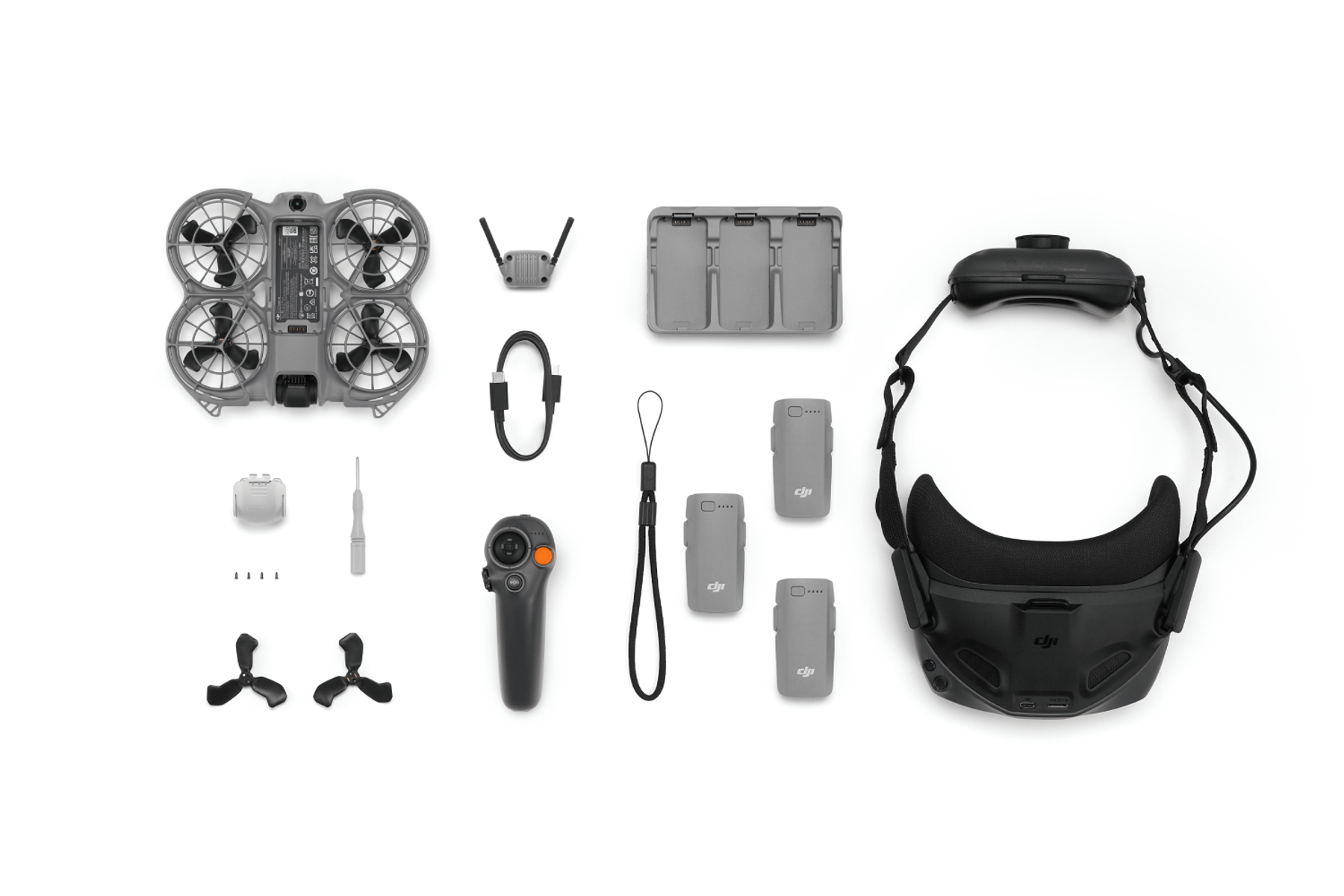 Elementy zestawu drona DJI: dron, gogle, pilot, baterie, ładowarka, kable i akcesoria, wszystko na białym tle.