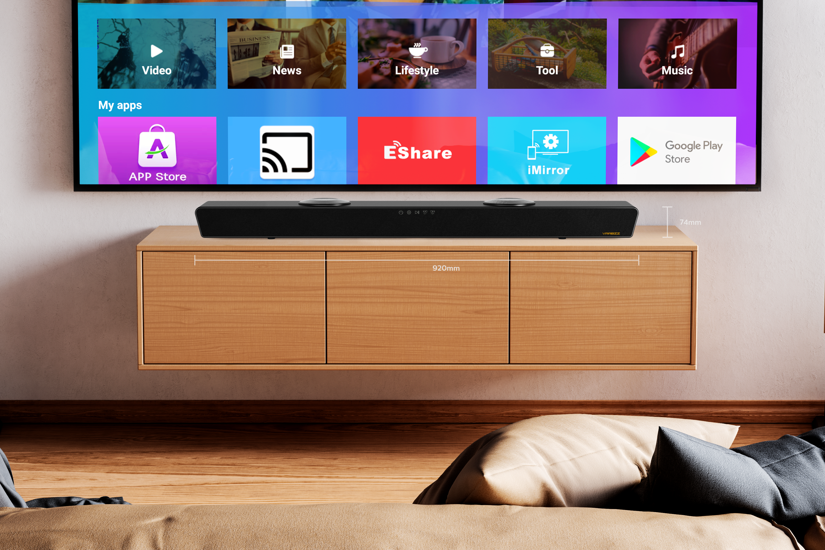 Ein Fernseher zeigt Apps. Darunter befindet sich eine Soundbar auf einem Holzschrank. Im Vordergrund ein Bett mit Kissen.