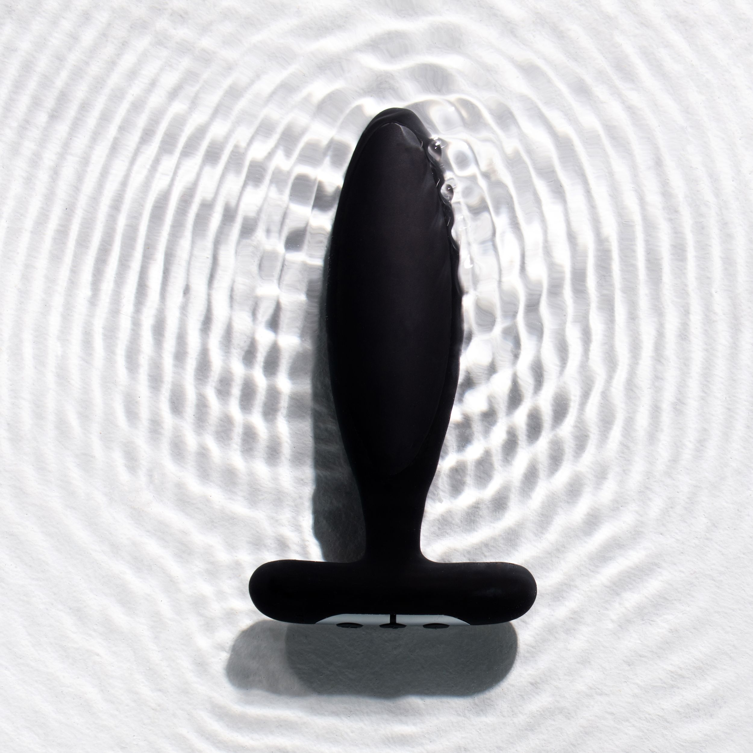 Schwarzes Analplug-Spielzeug schwimmt in Wasser mit Wellen.