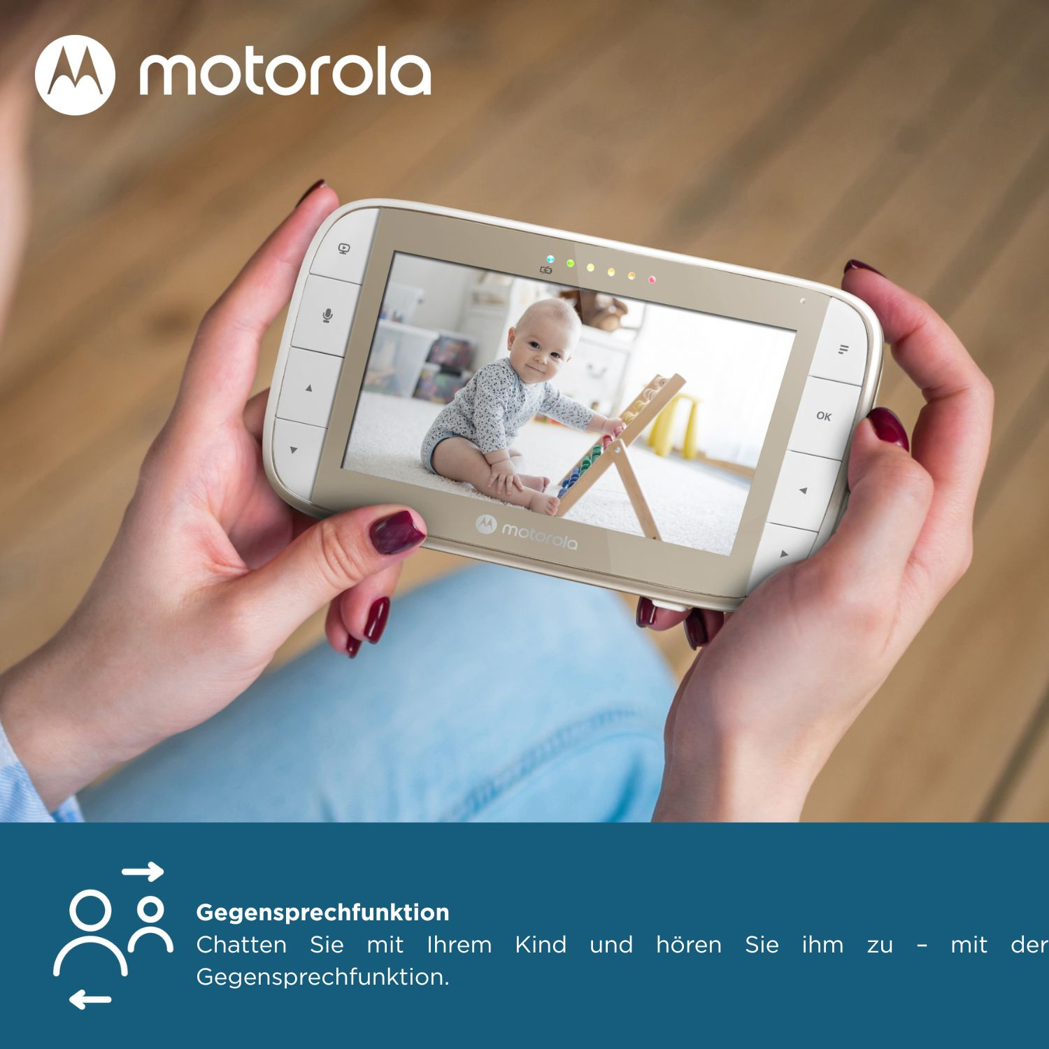 Una persona sostiene un monitor para bebés que muestra un bebé. El monitor tiene botones. El logotipo de Motorola es visible. Se ven manos y una camisa azul.