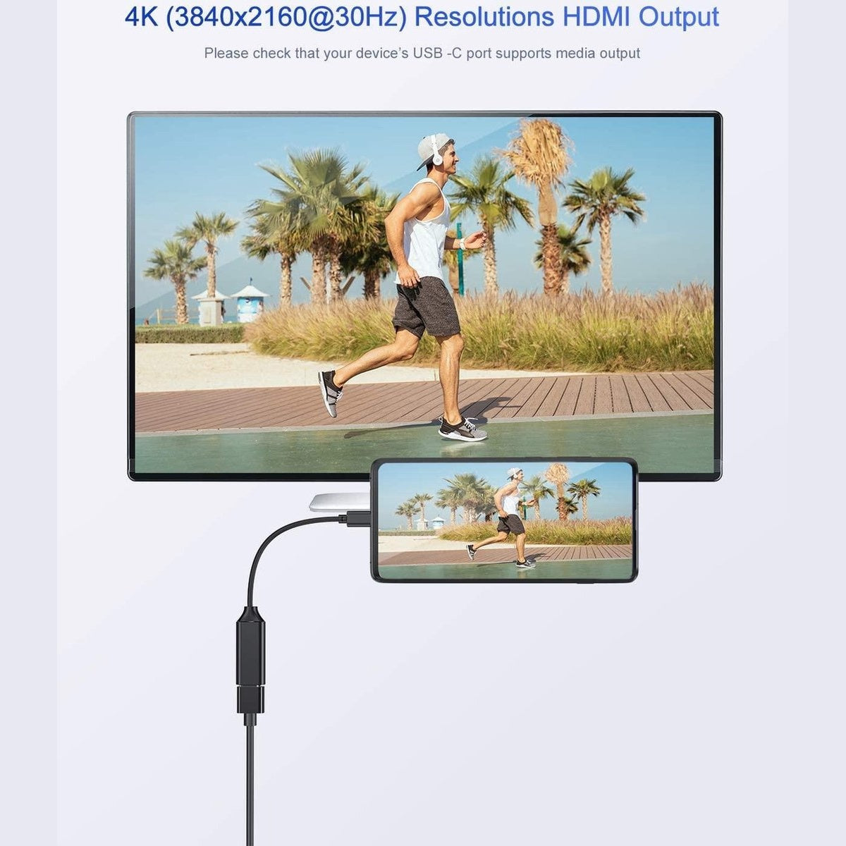 Een man die op het strand rent, wordt weergegeven op een scherm en een telefoon. Kabel verbindt telefoon met scherm. Palmbomen en blauwe lucht.