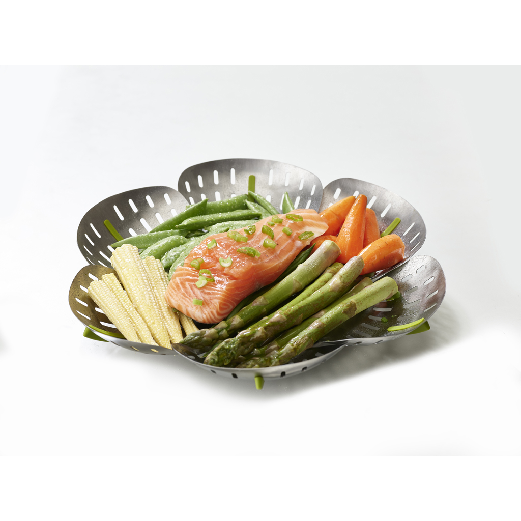 Ein Metalldämpfer gefüllt mit Lachs, Spargel, Karotten, grünen Bohnen und Mais. Alles auf weißem Hintergrund.