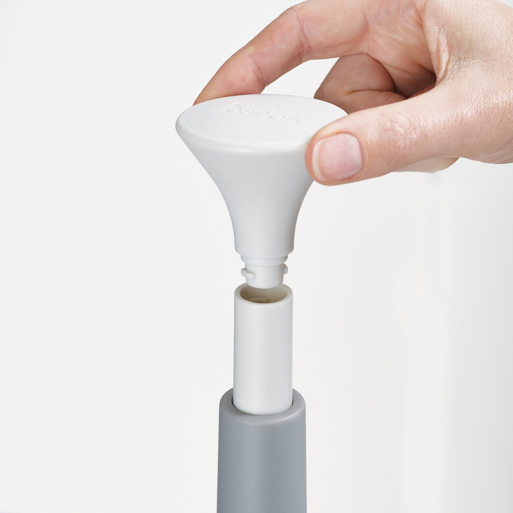 Mano che tiene un utensile da cucina in plastica bianca, assembla le parti. La base è grigia, il centro bianco e la parte superiore una maniglia bianca.
