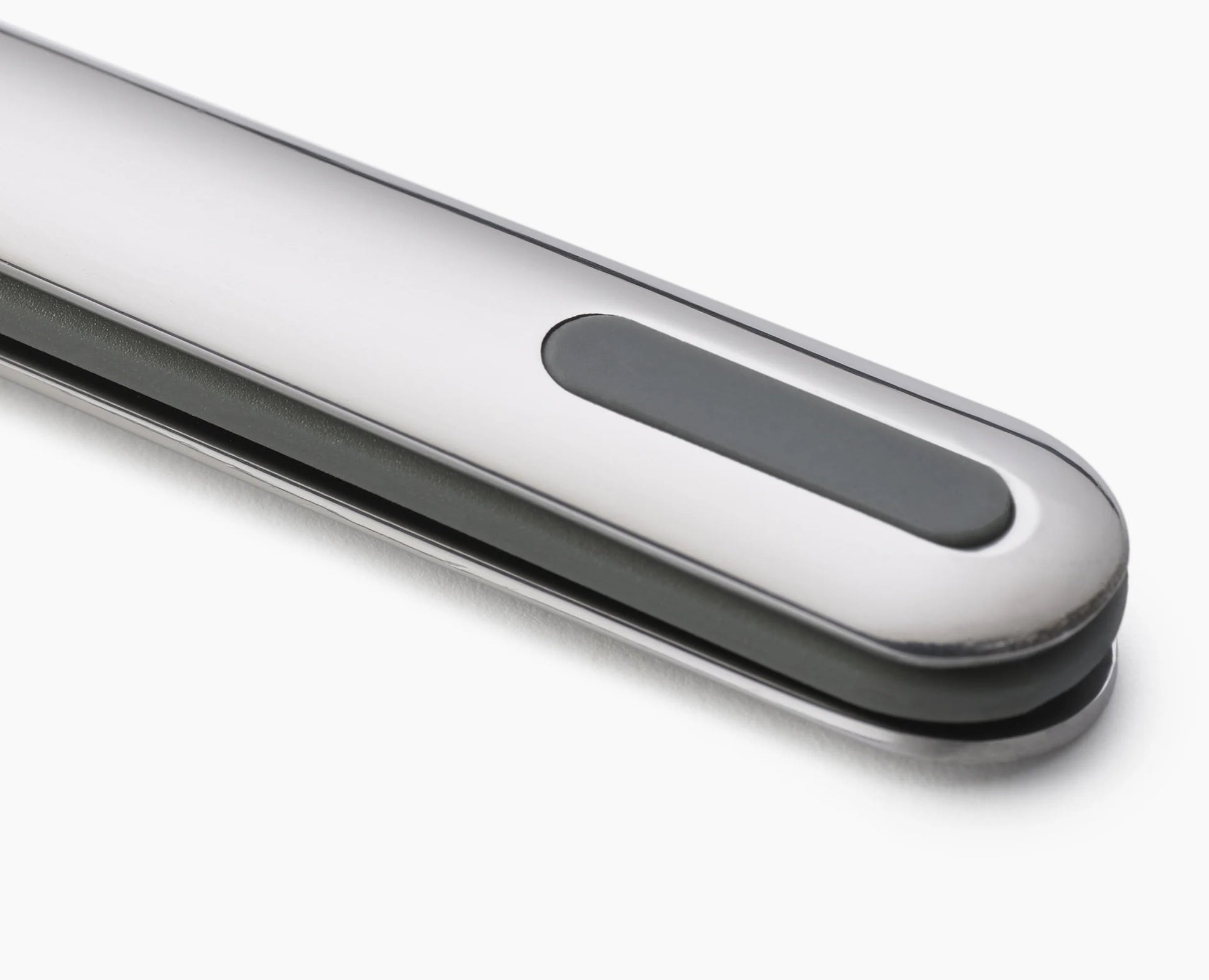 Primer plano de un objeto plateado con una incrustación rectangular gris oscuro sobre fondo blanco.