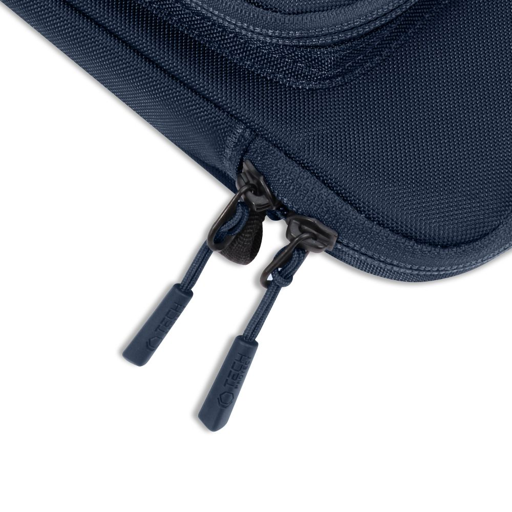 Gros plan d'un sac bleu marine avec deux fermetures éclair noires. Chaque fermeture éclair a une tirette marine avec le mot 'TECH'.