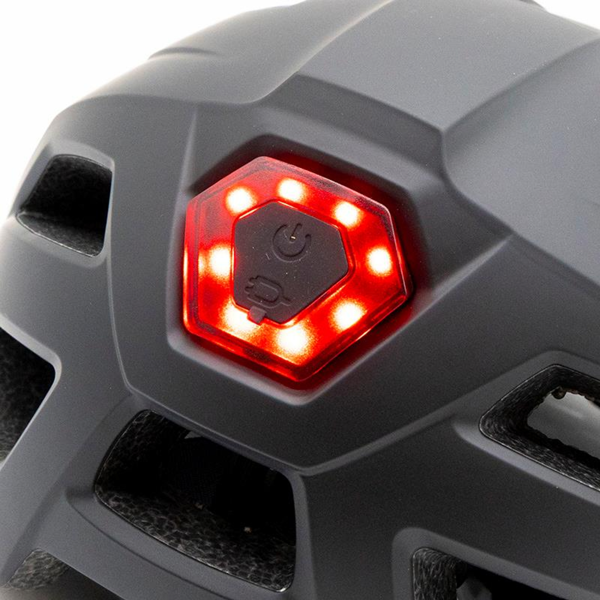 Primer plano de un casco gris oscuro con un panel de luz rojo e iluminado en la parte trasera. El panel tiene símbolos de encendido y carga.