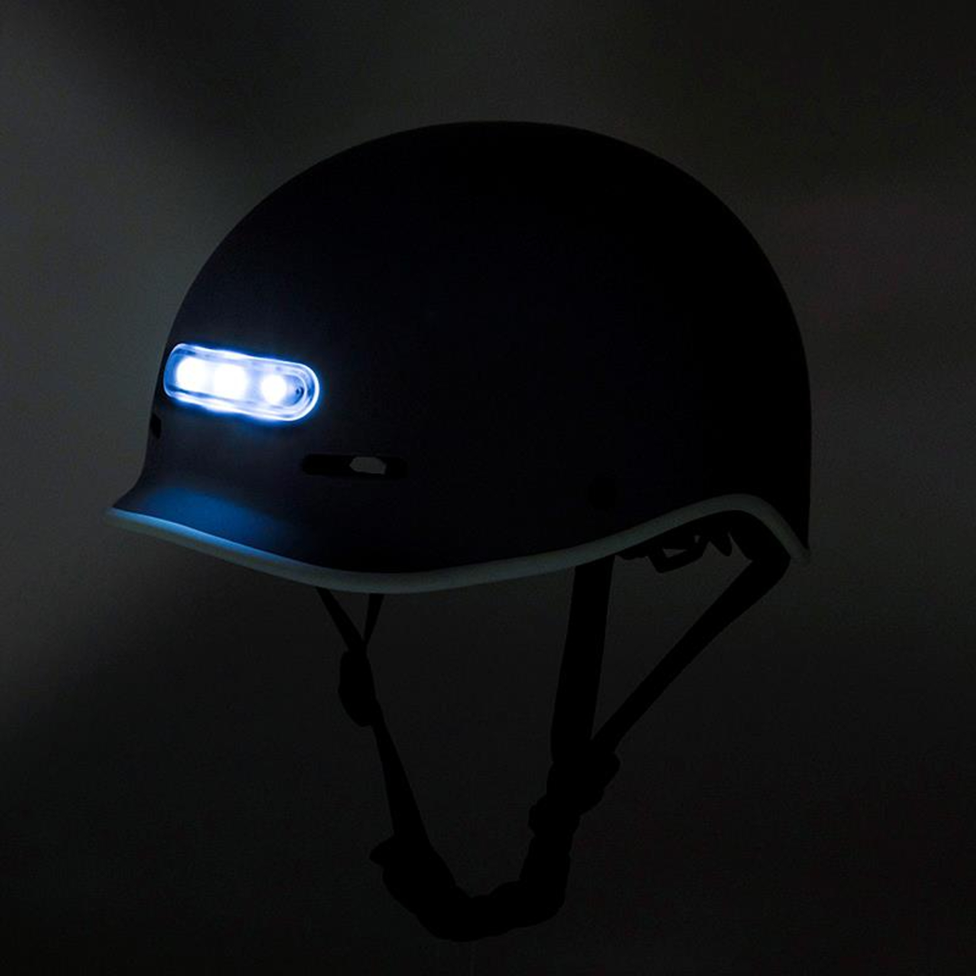Un casco de bicicleta negro con una luz blanca brillante en la parte delantera y una moldura blanca.