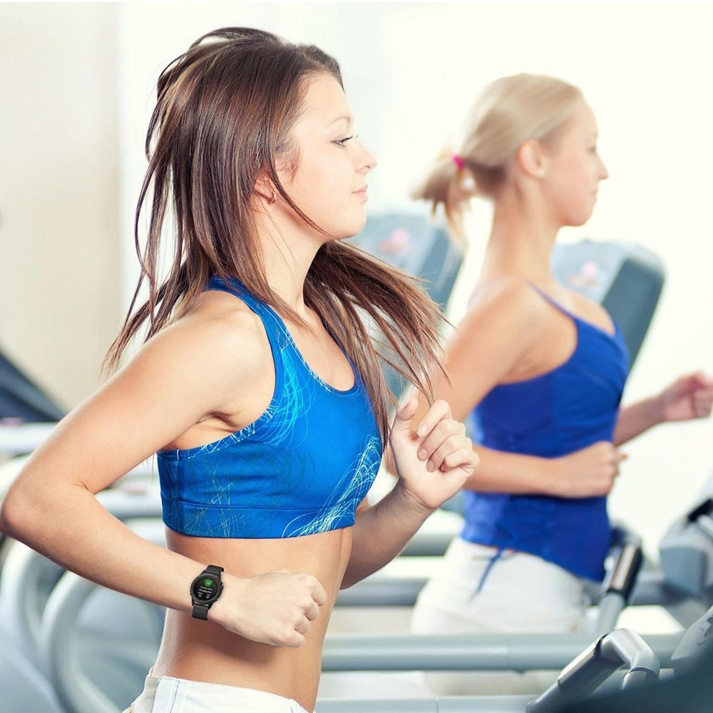 Due donne corrono su tapis roulant. Una indossa un reggiseno sportivo blu e uno smartwatch. L'altra indossa una canotta blu.