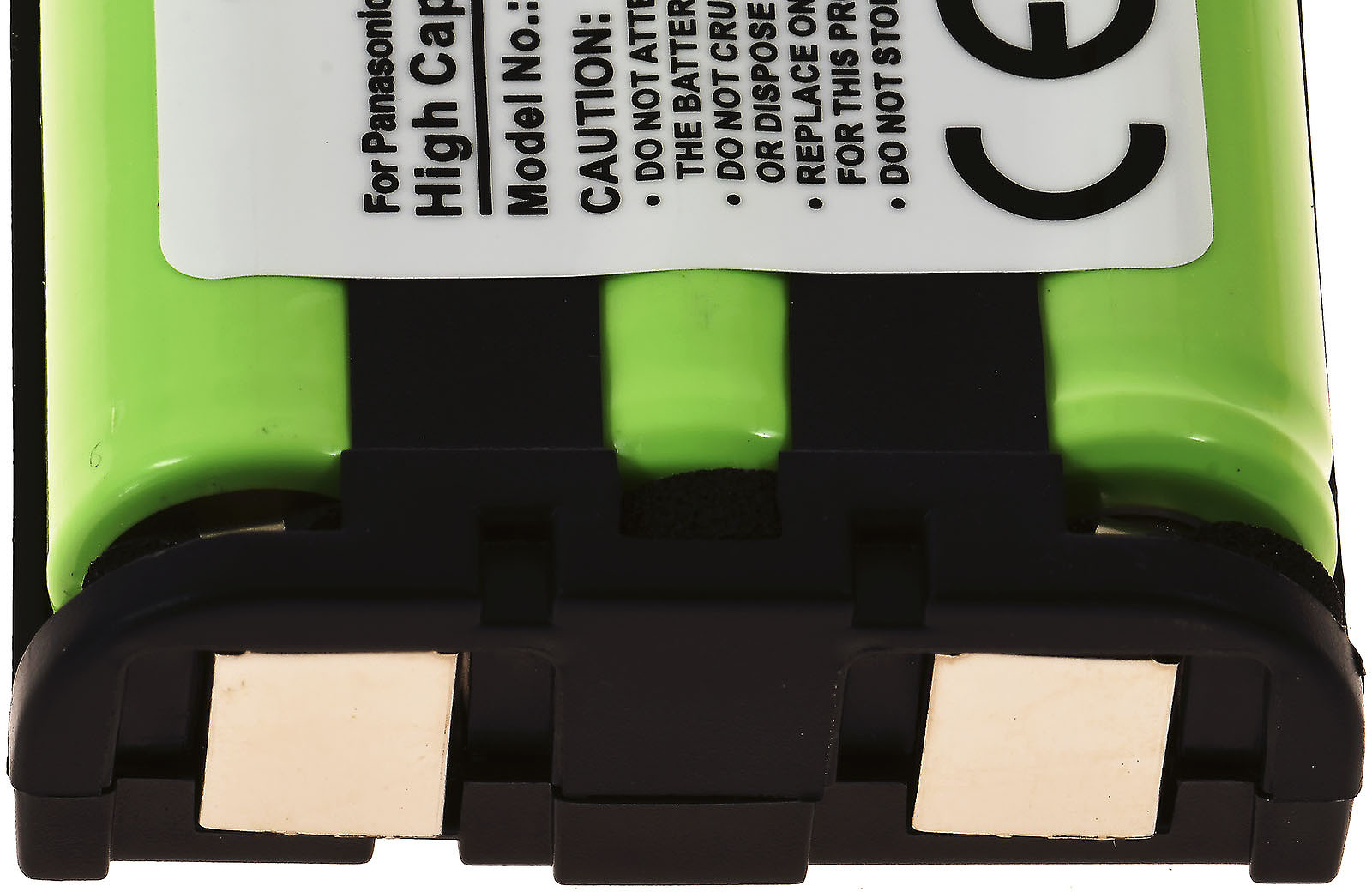 Primer plano de una batería verde y negra. Tiene una etiqueta blanca con texto y una marca CE. Tiene una base de plástico negro con contactos color canela.