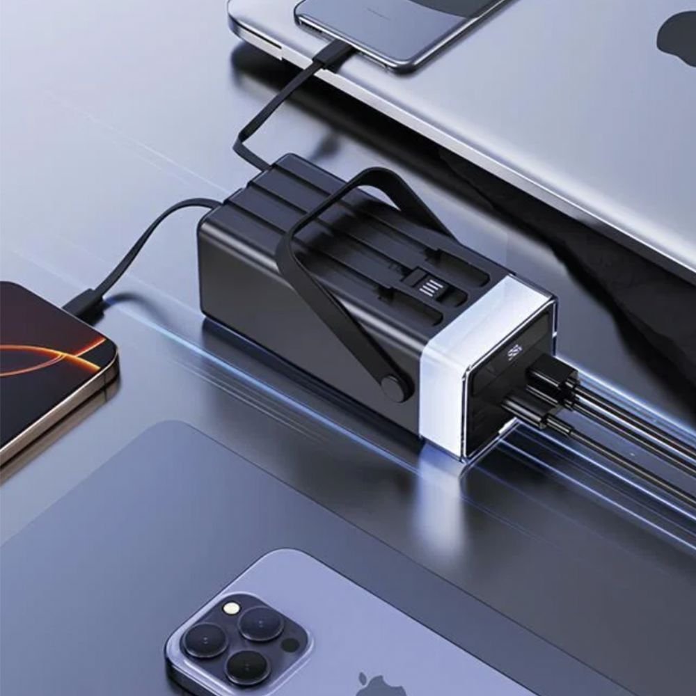 Siyah güç bankası birden fazla cihazı şarj ediyor: telefon, tablet. Gümüş ve siyah tasarım. Kablolar bağlı. Parlak yüzey.