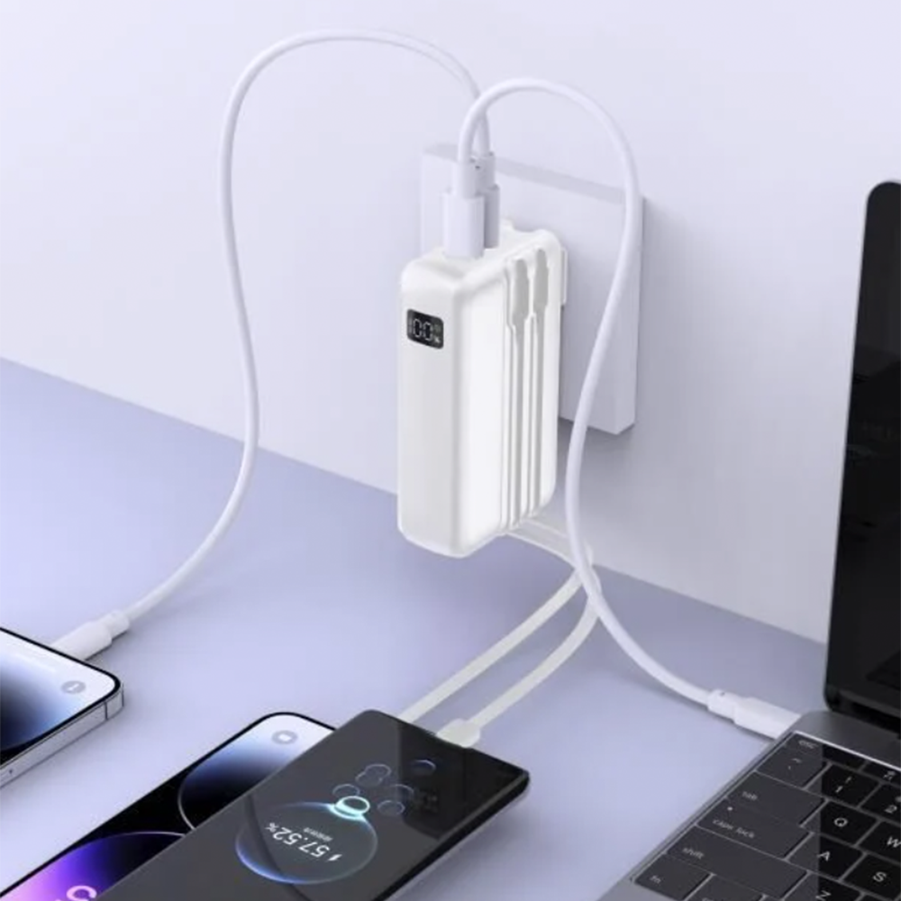 Beyaz bir powerbank birden fazla cihazı şarj ediyor: telefonlar ve bir dizüstü bilgisayar. Powerbank, %100 gösteren bir duvar prizine takılı.