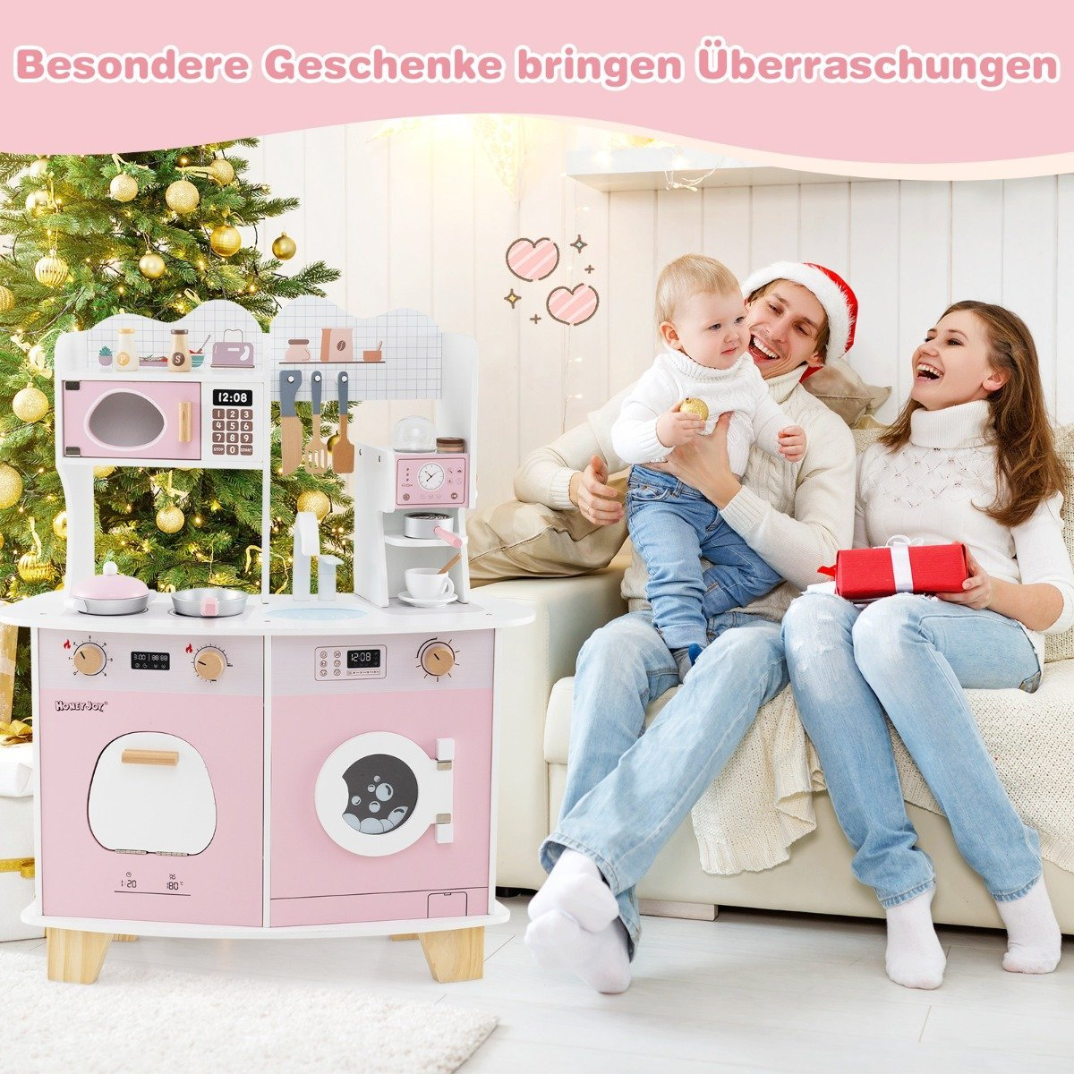 Una familia con un bebé está frente a una cocina de juguete. Hay un árbol de Navidad en el fondo. Se sostiene un regalo.