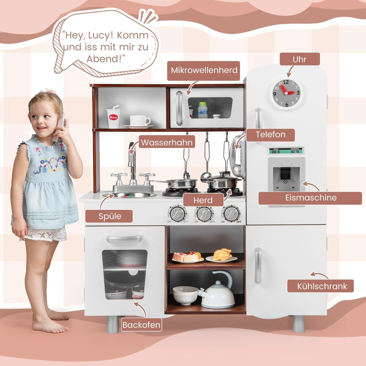 Una niña habla por un teléfono de juguete cerca de una cocina de juguete. La cocina tiene microondas, estufa, fregadero y refrigerador.