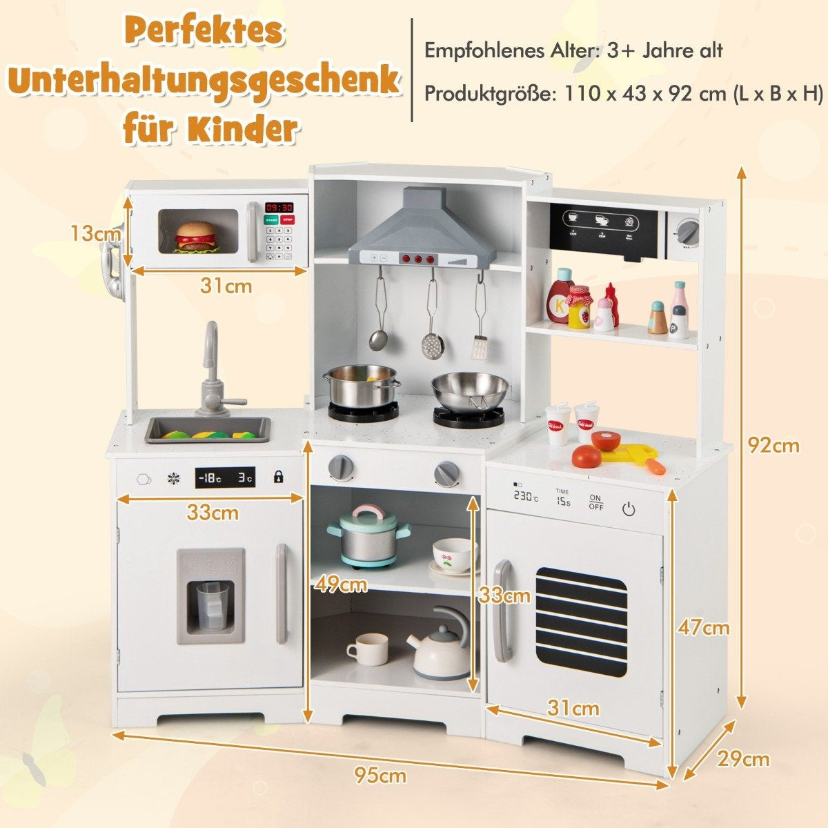 Una cocina de juguete blanca con microondas, fregadero, estufa y refrigerador, con medidas en centímetros. Algunos utensilios de cocina.