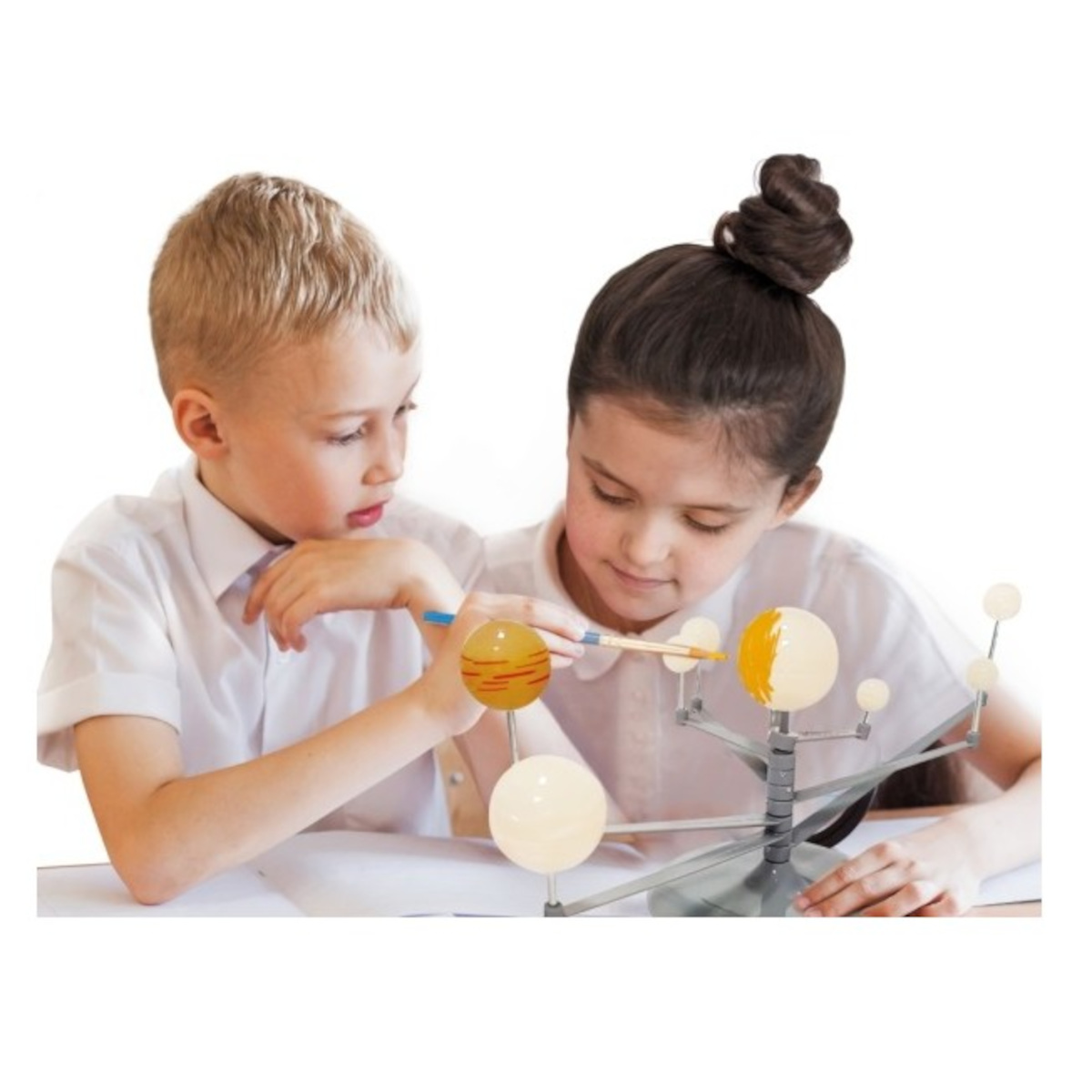 Zwei Kinder untersuchen ein Sonnensystemmodell. Einer zeigt mit einem Stift auf einen Planeten. Der andere schaut sich das Modell an. Weiße Hemden.