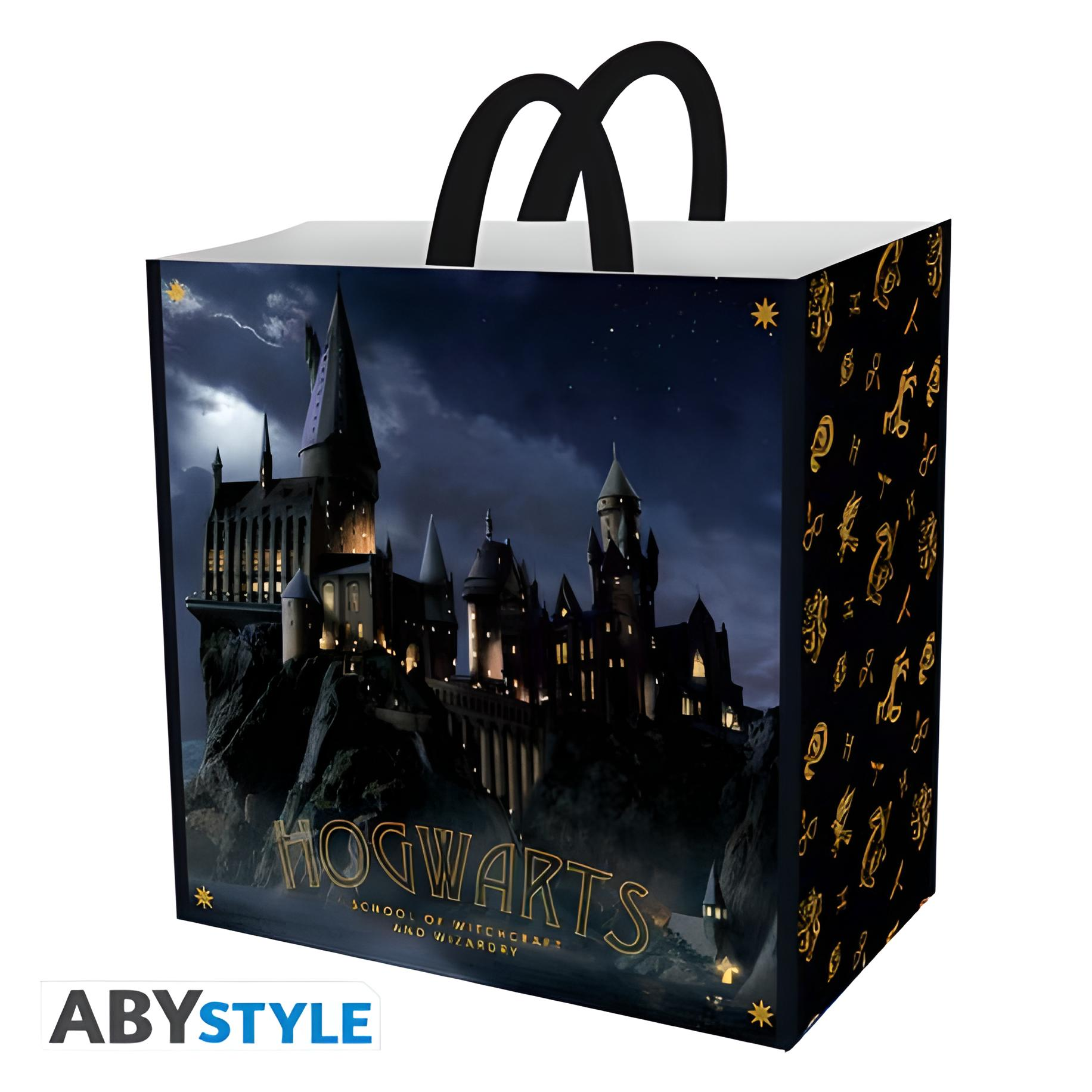 Einkaufstasche mit Hogwarts-Schloss. Schwarze Griffe. Dunkler Hintergrund mit Sternen und Blitzen.