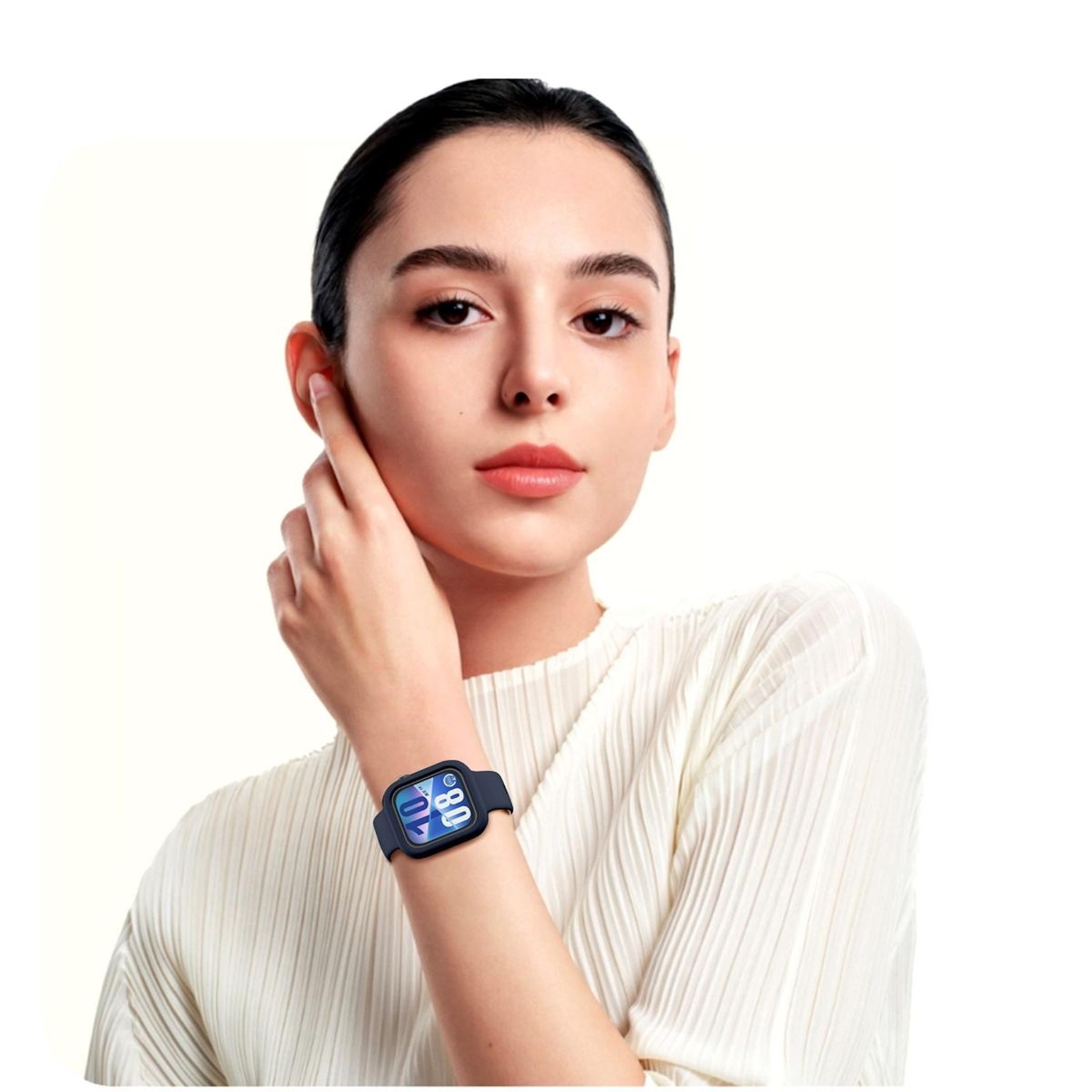 Una donna con uno smartwatch si tocca l'orecchio. L'orologio mostra un'interfaccia digitale. Indossa un top bianco.